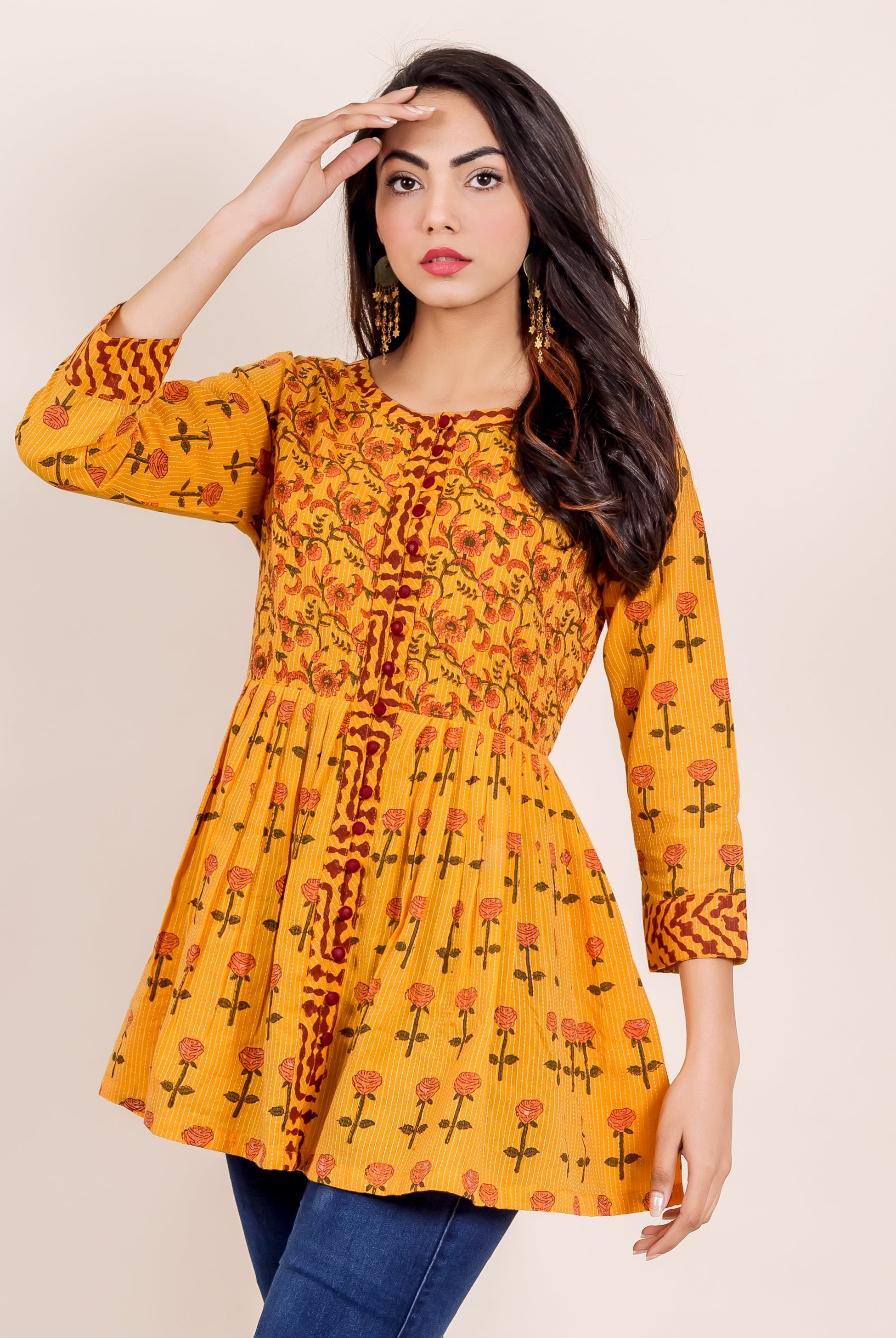 Three-quarter shot of model wearing a vibrant yellow hand-block printed peplum top with rose print.