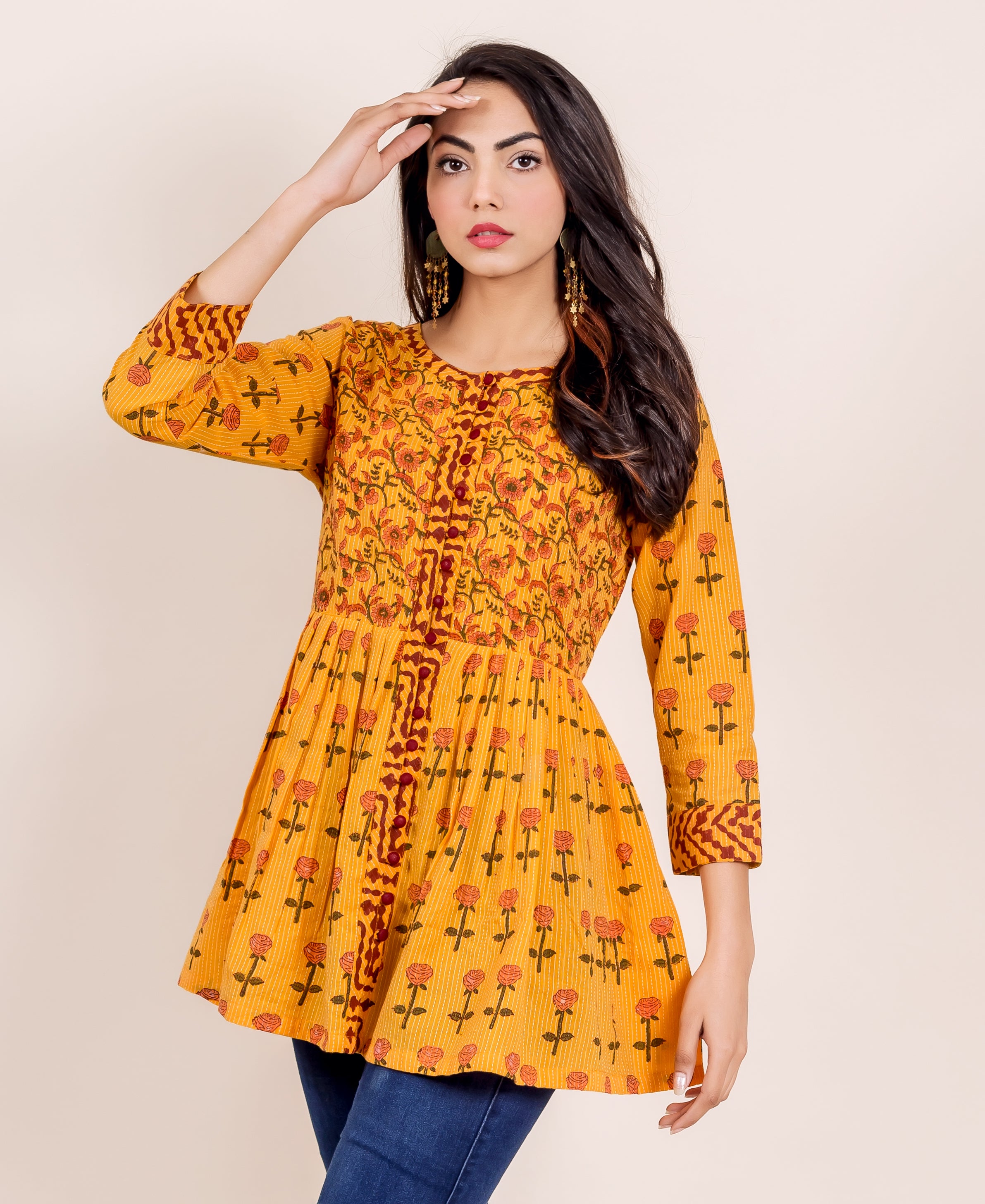 Three-quarter shot of model wearing a vibrant yellow hand-block printed peplum top with rose print.