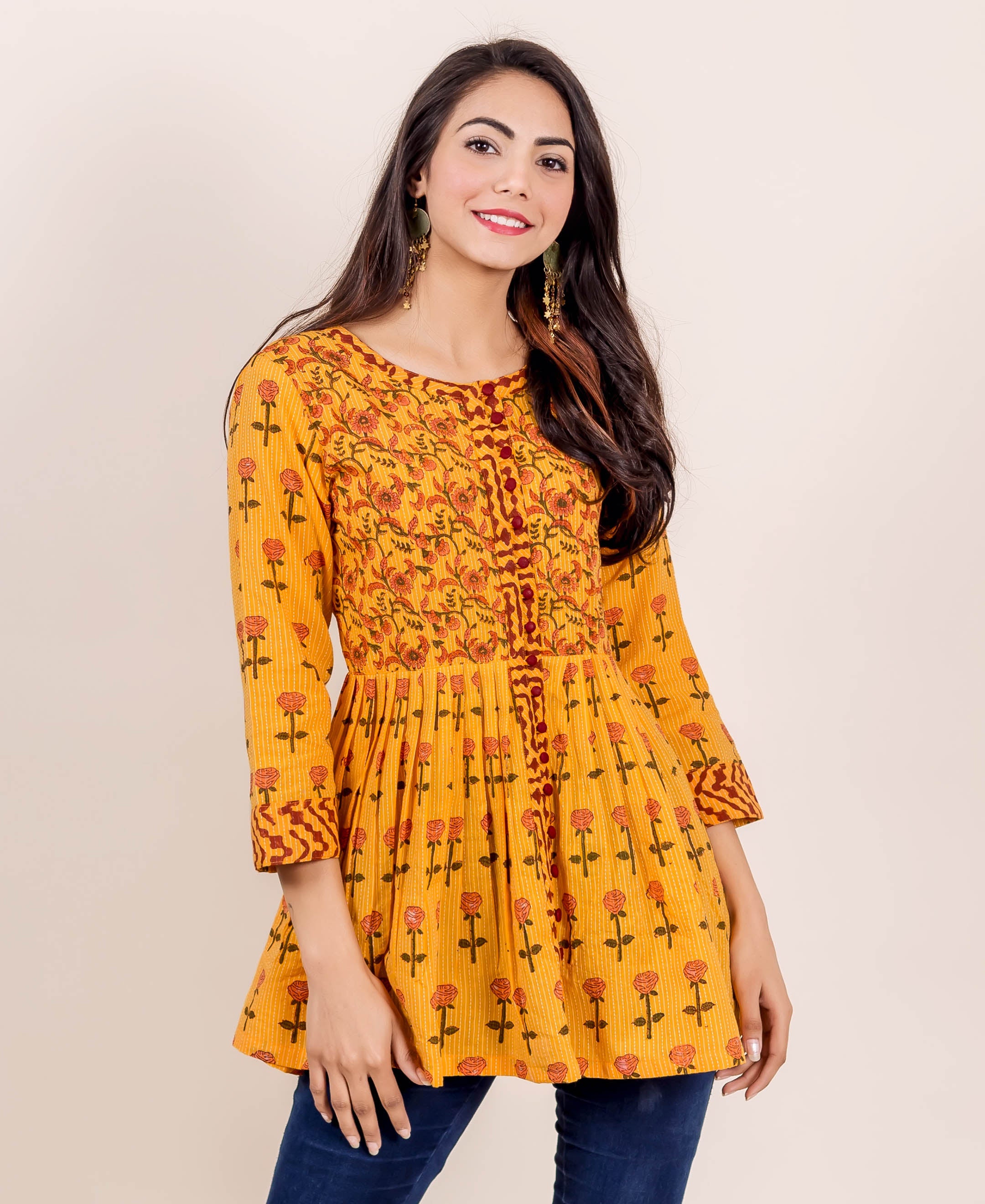 Smiling model in a yellow hand block printed peplum top with red floral patterns.