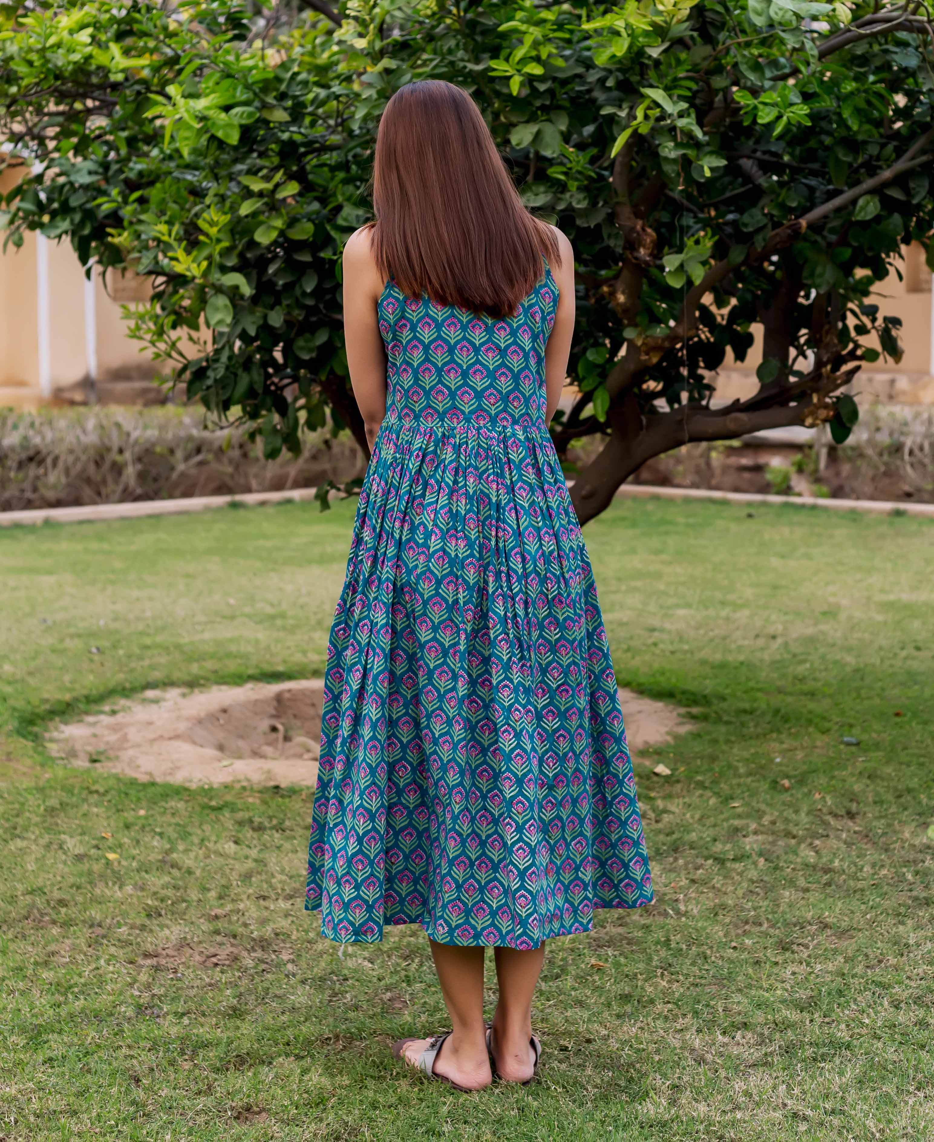 Model from back in a teal sleeveless midi dress with purple hand block print.