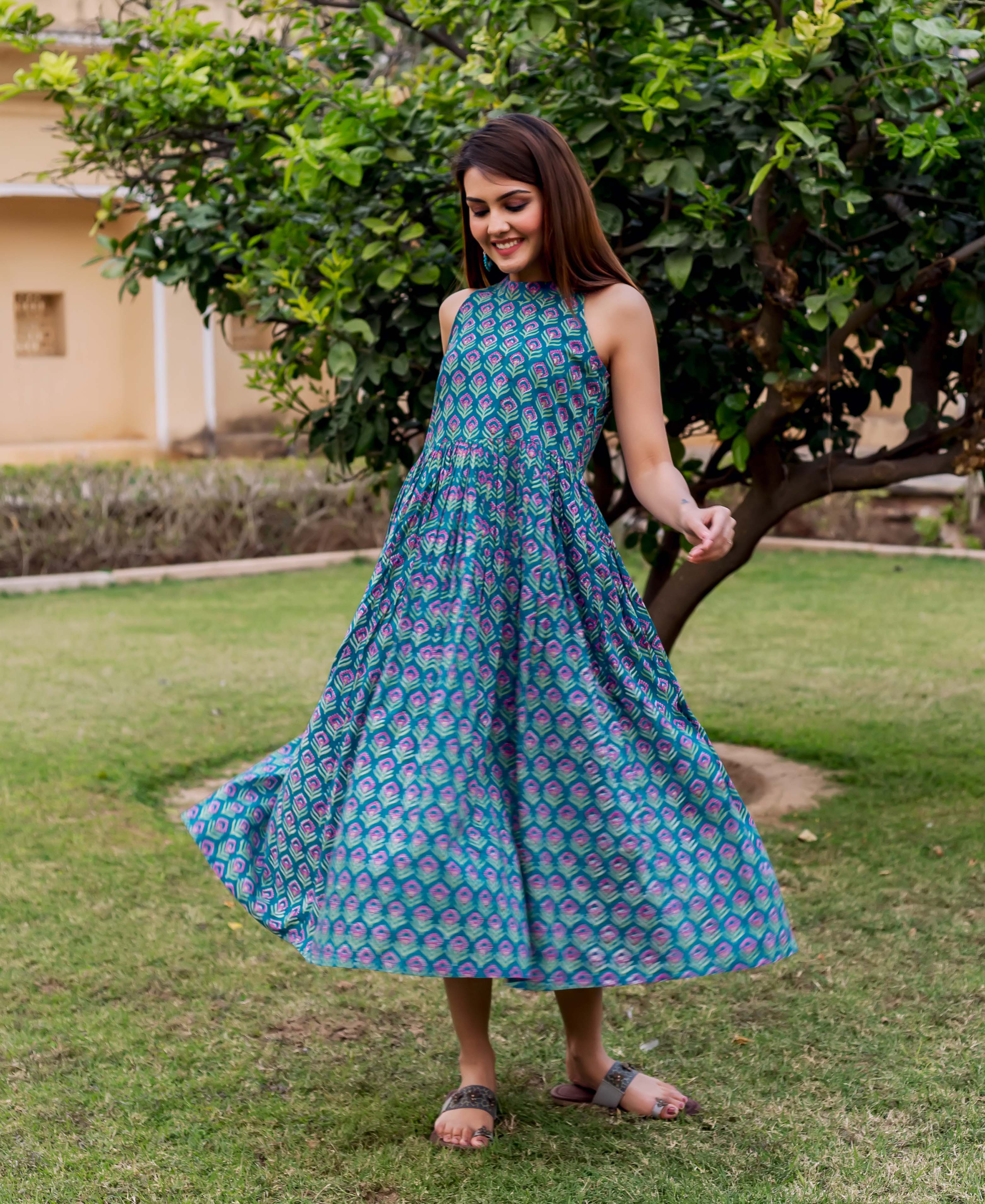 Model twirling in a teal halter neck dress with purple hand block print.