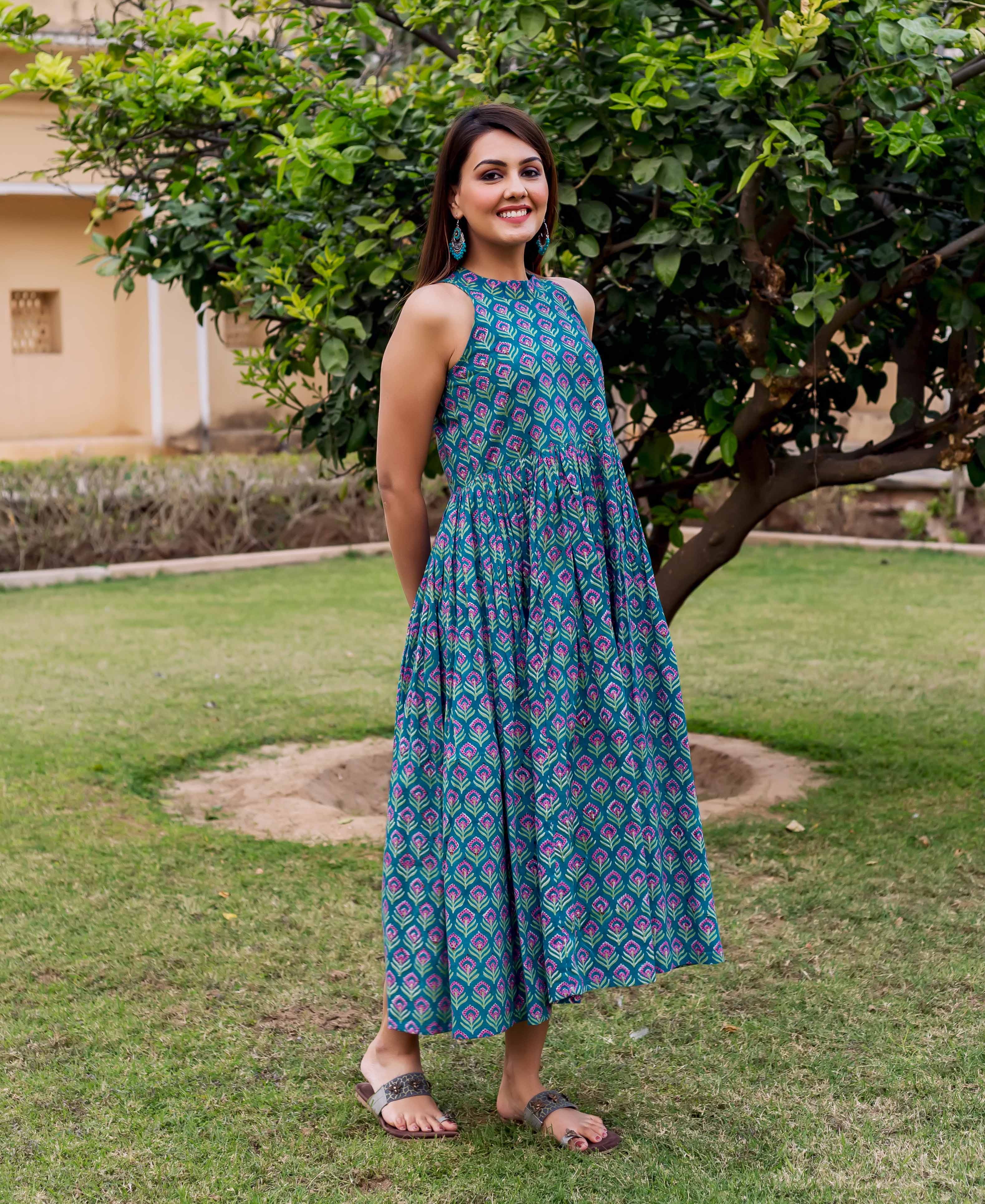 Smiling model wears a teal halter neck dress with purple hand block print pattern.