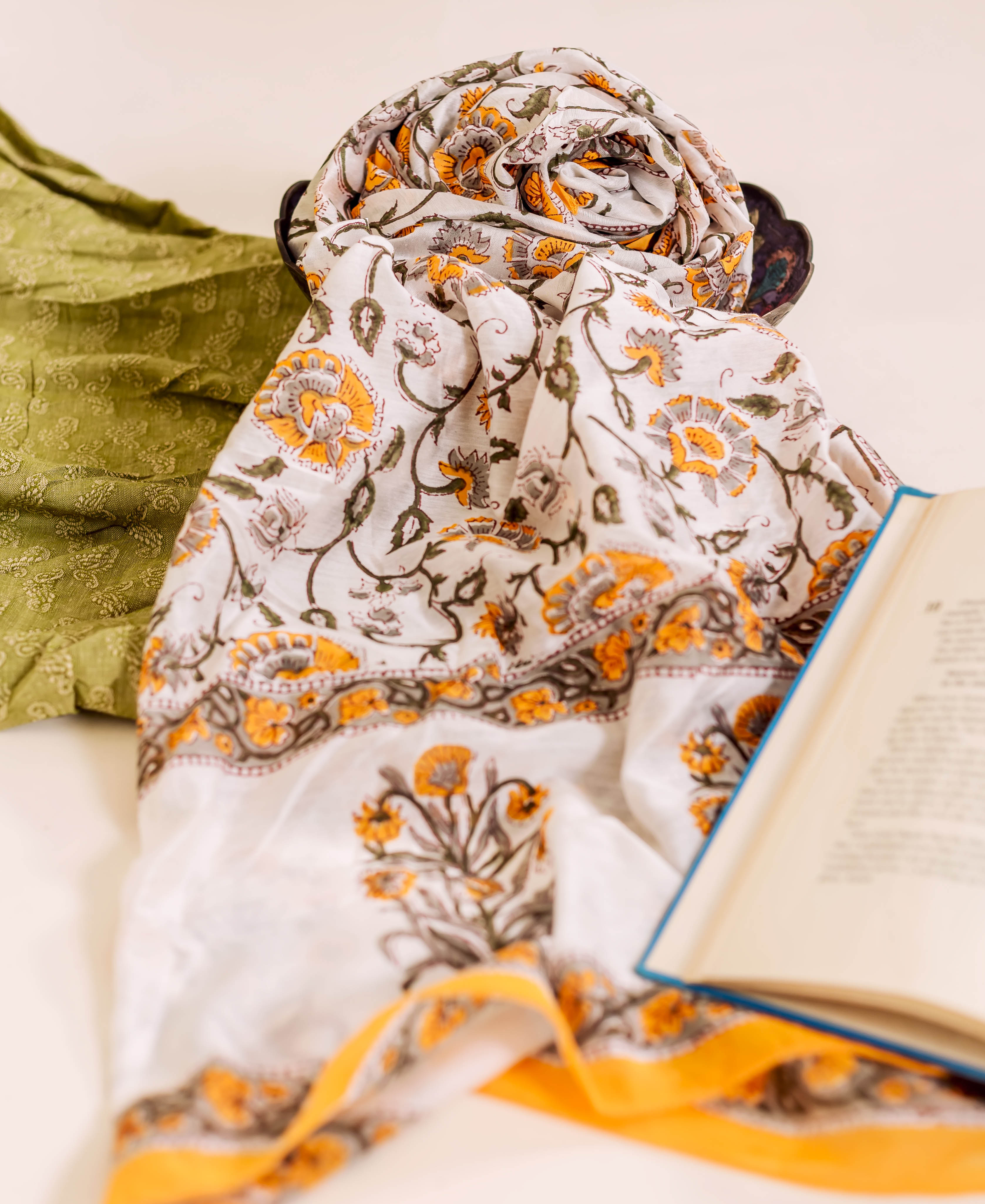 Overhead view of a draped white and yellow block-printed chanderi dupatta with floral designs.