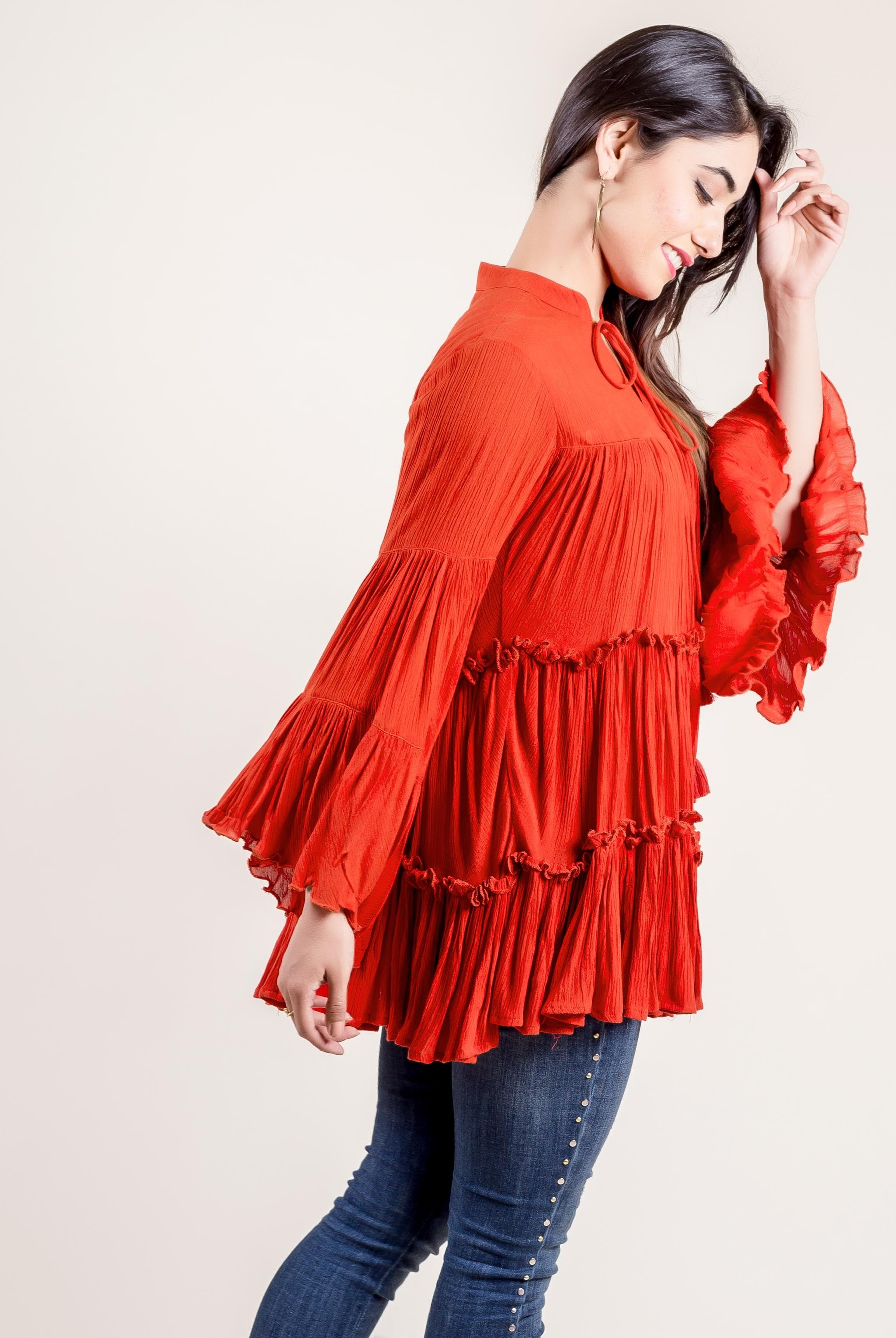 A model wearing a rust-colored, hand-block-printed rayon frill top with tassels.