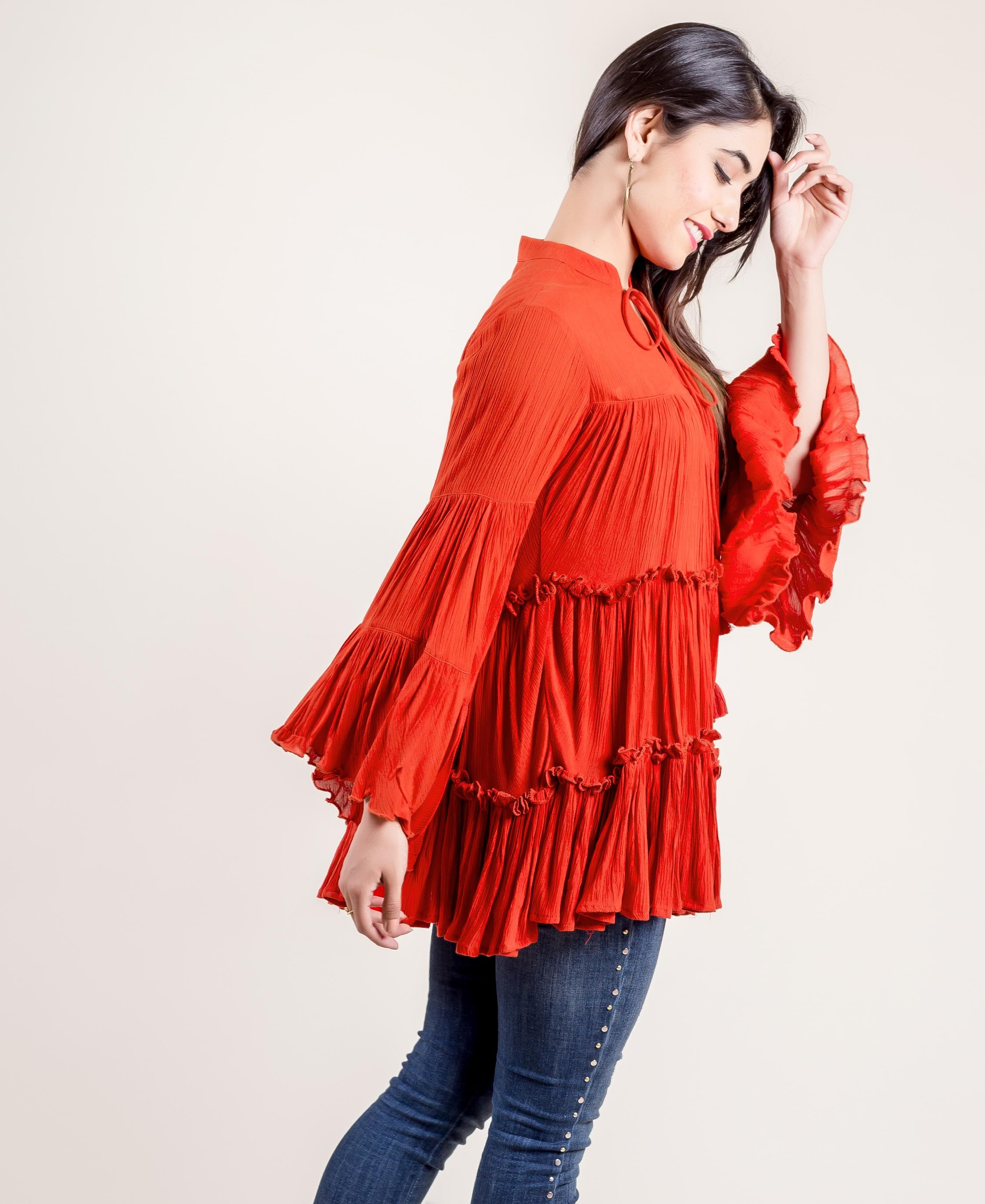 A model wearing a rust-colored, hand-block-printed rayon frill top with tassels.