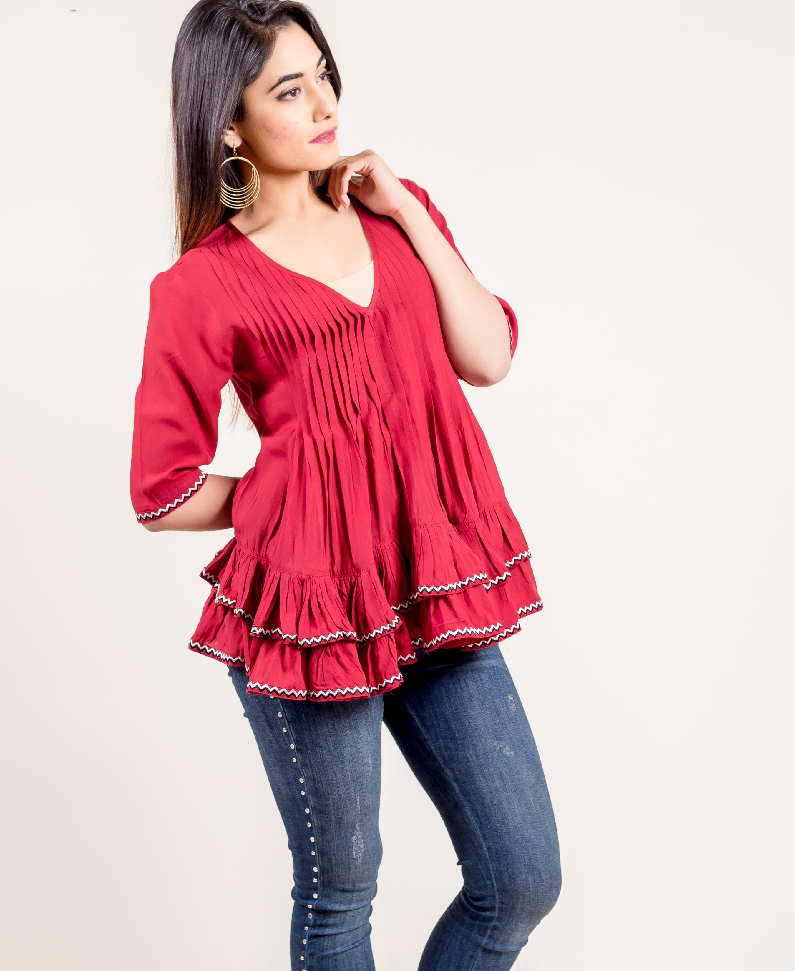 Model wears a vibrant red pleated frilled top with zigzag ethnic trim.