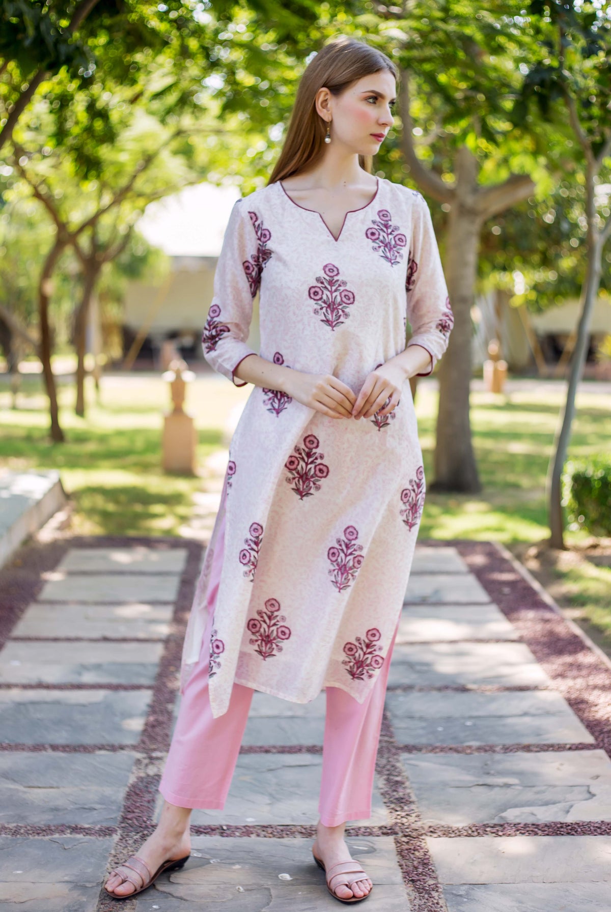 Full-length model in a white kurta with pink-maroon floral block prints and pink pants.