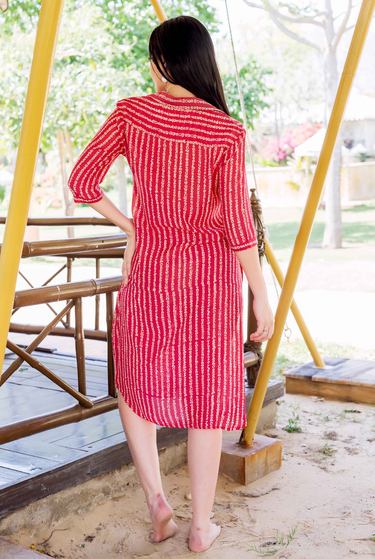 Back view of model wearing red ethnic dress with vertical hand-block-printed pattern.