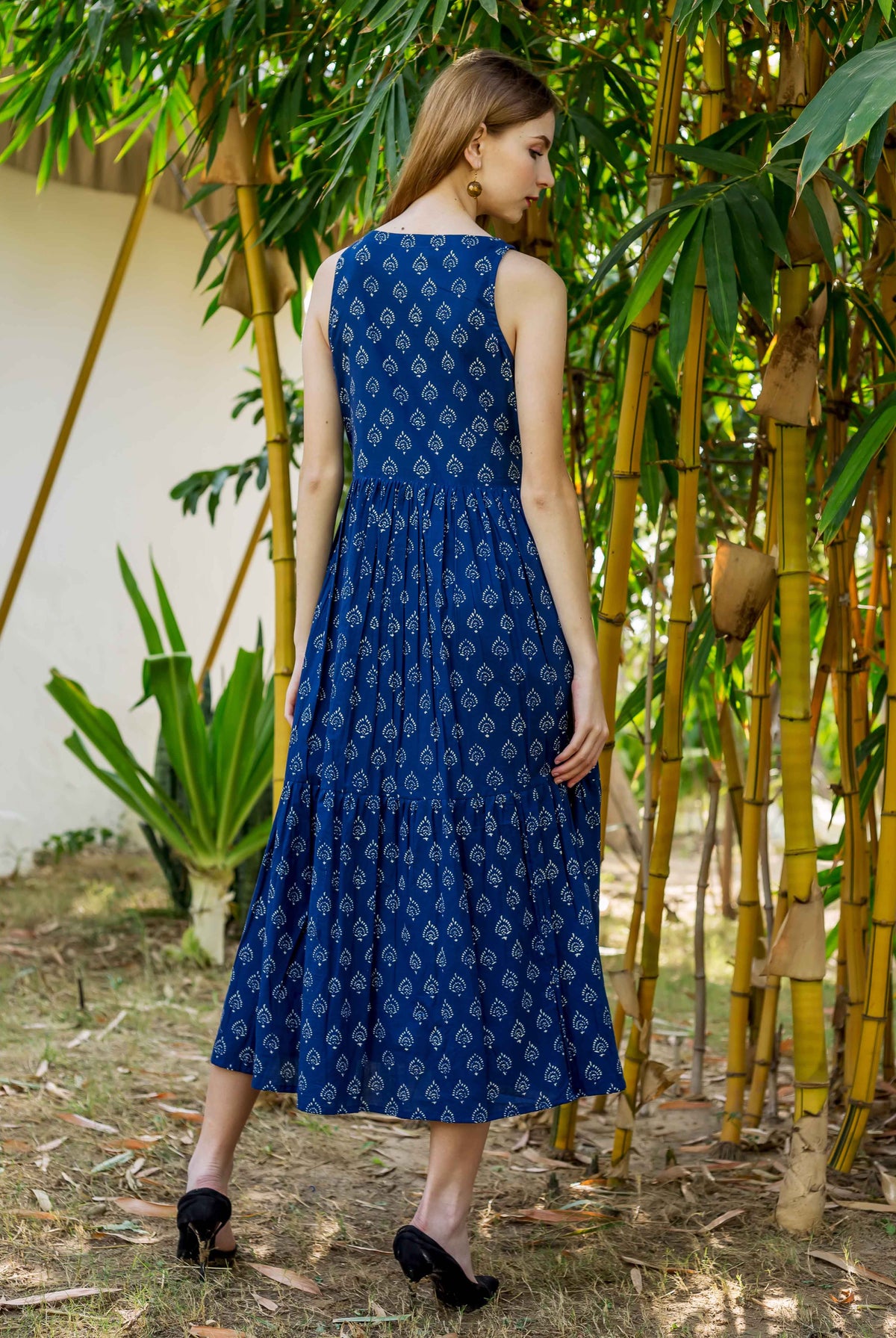 Back view of model wearing indigo hand block printed sleeveless tiered dress.