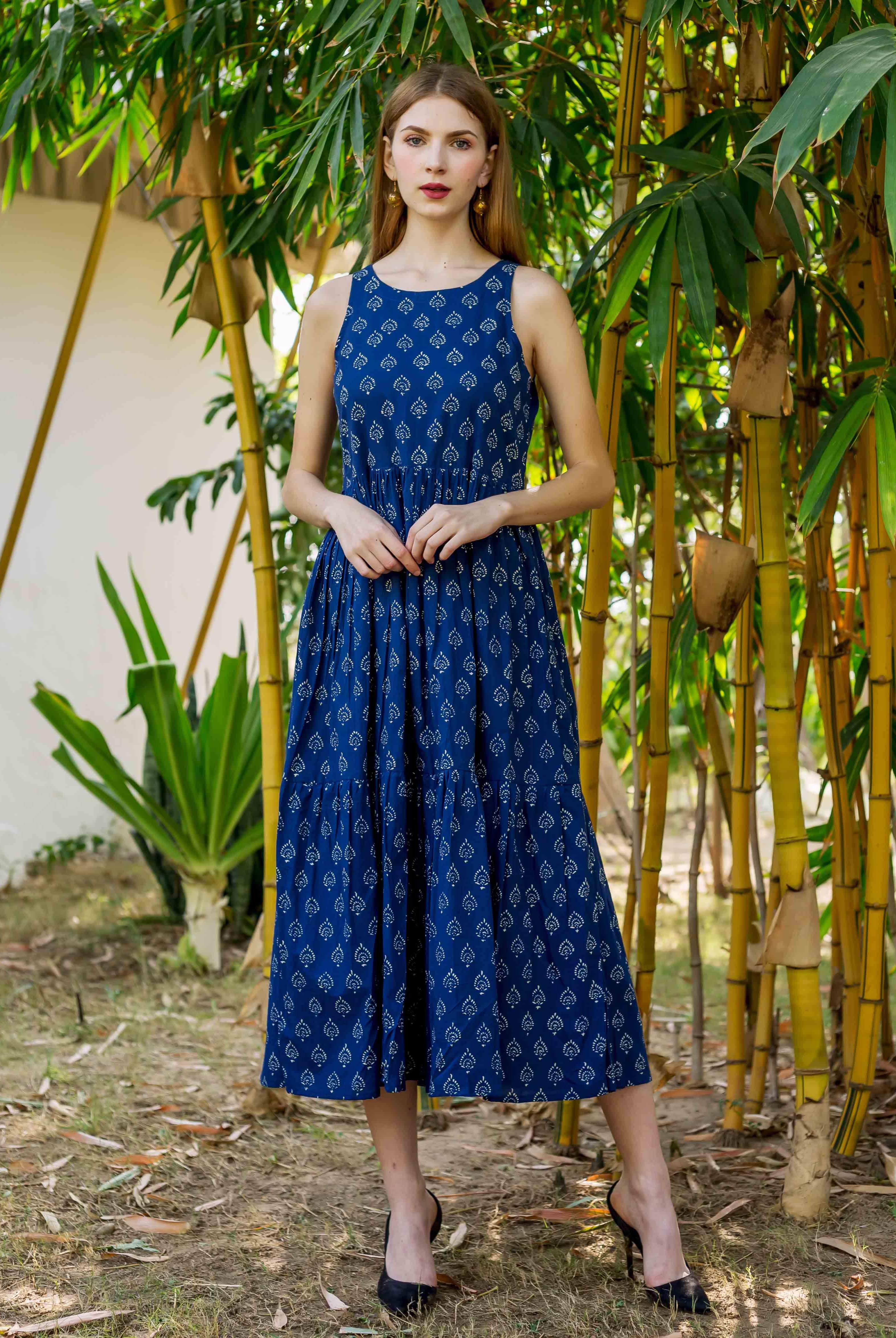 Full body shot of model wearing an indigo blue sleeveless tiered dress with white hand block print.