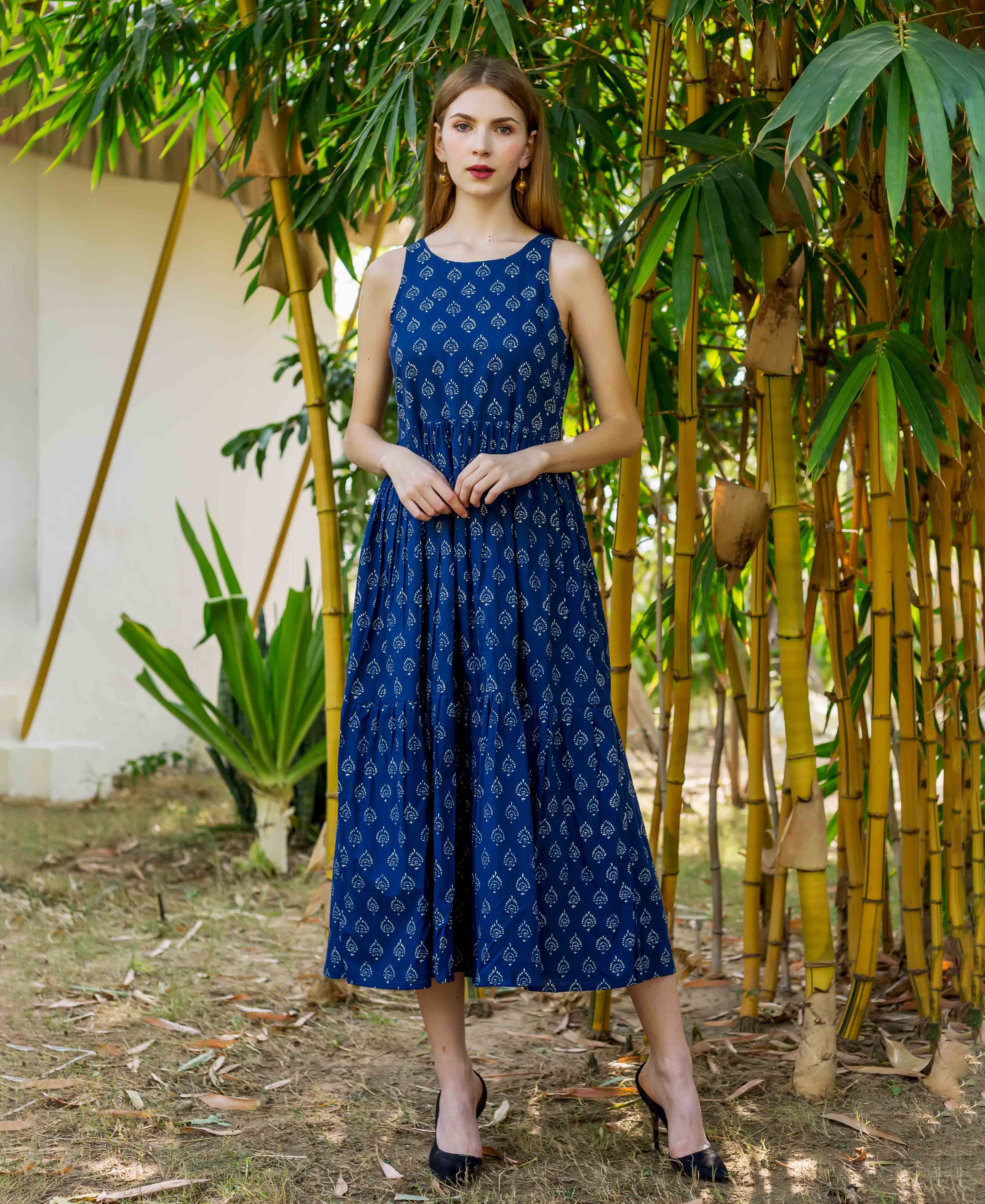 Full body shot of model wearing an indigo blue sleeveless tiered dress with white hand block print.
