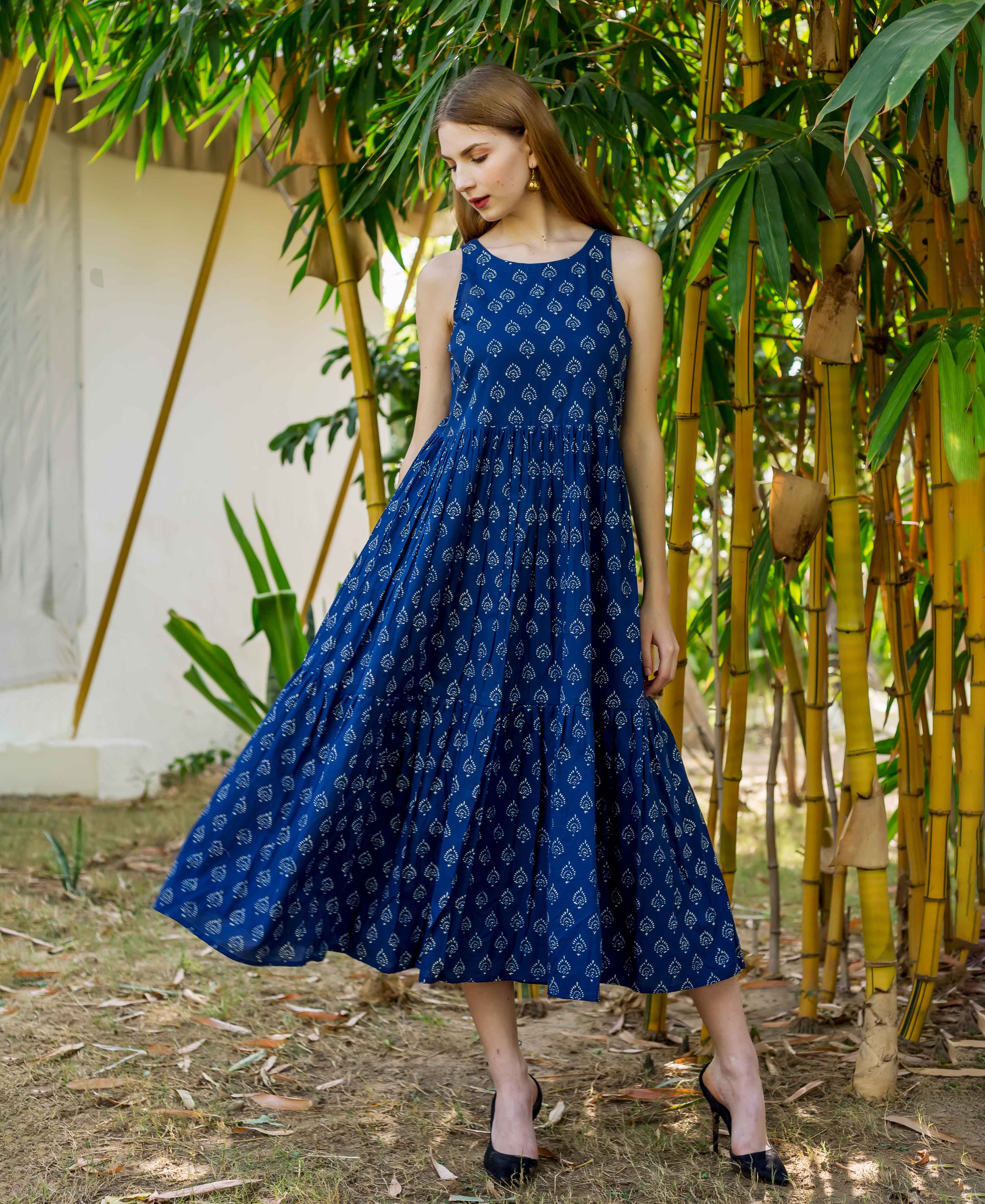 Woman wearing an indigo blue sleeveless tiered dress with white hand block prints.