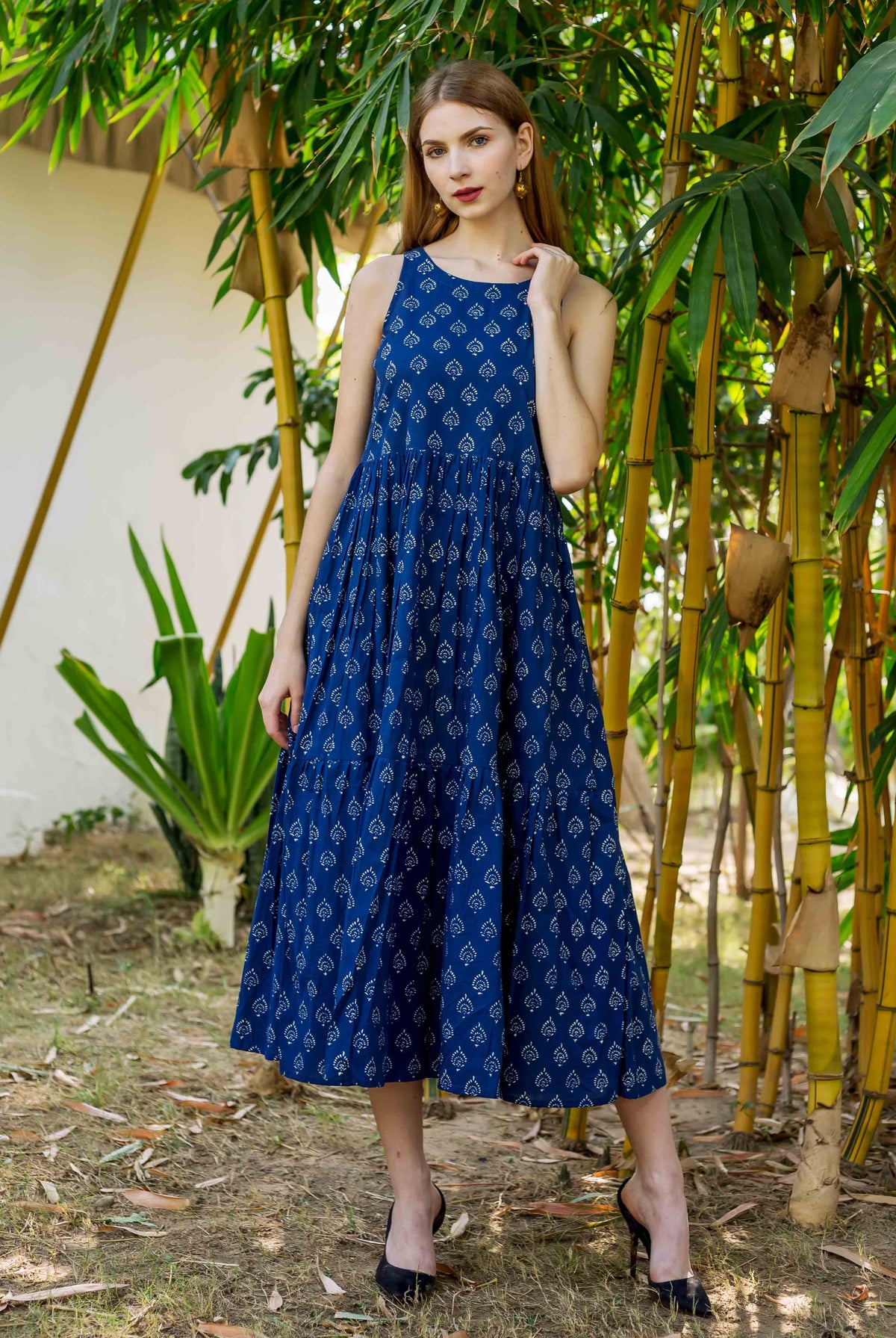 Full-length model wearing an indigo hand block printed sleeveless tiered dress.
