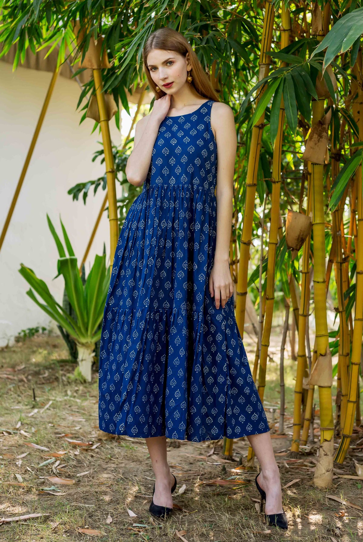 Front view of model wearing full indigo blue sleeveless tiered dress with white hand block print.