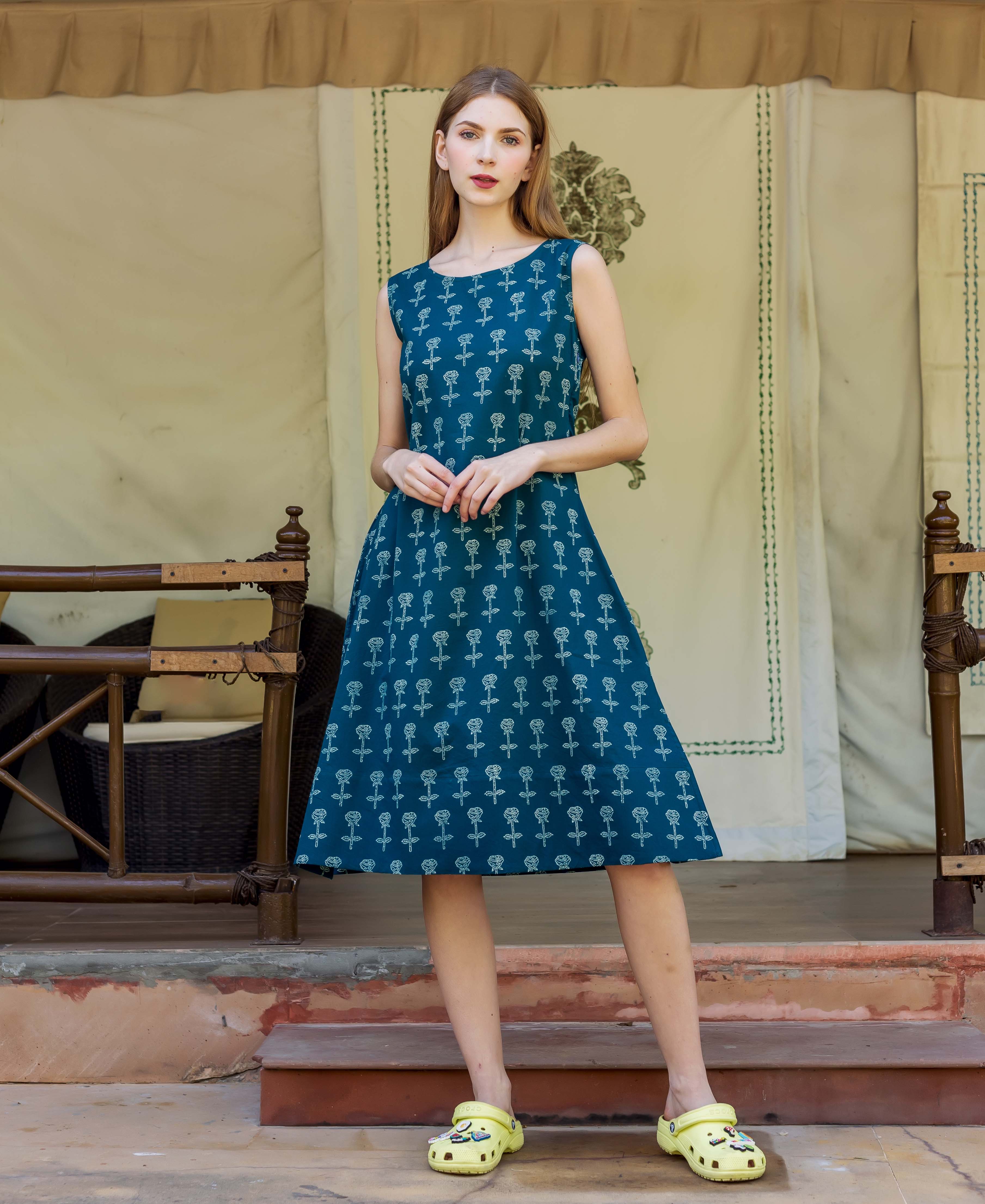 Front view of model wearing a teal A-line dress with white rose block print.