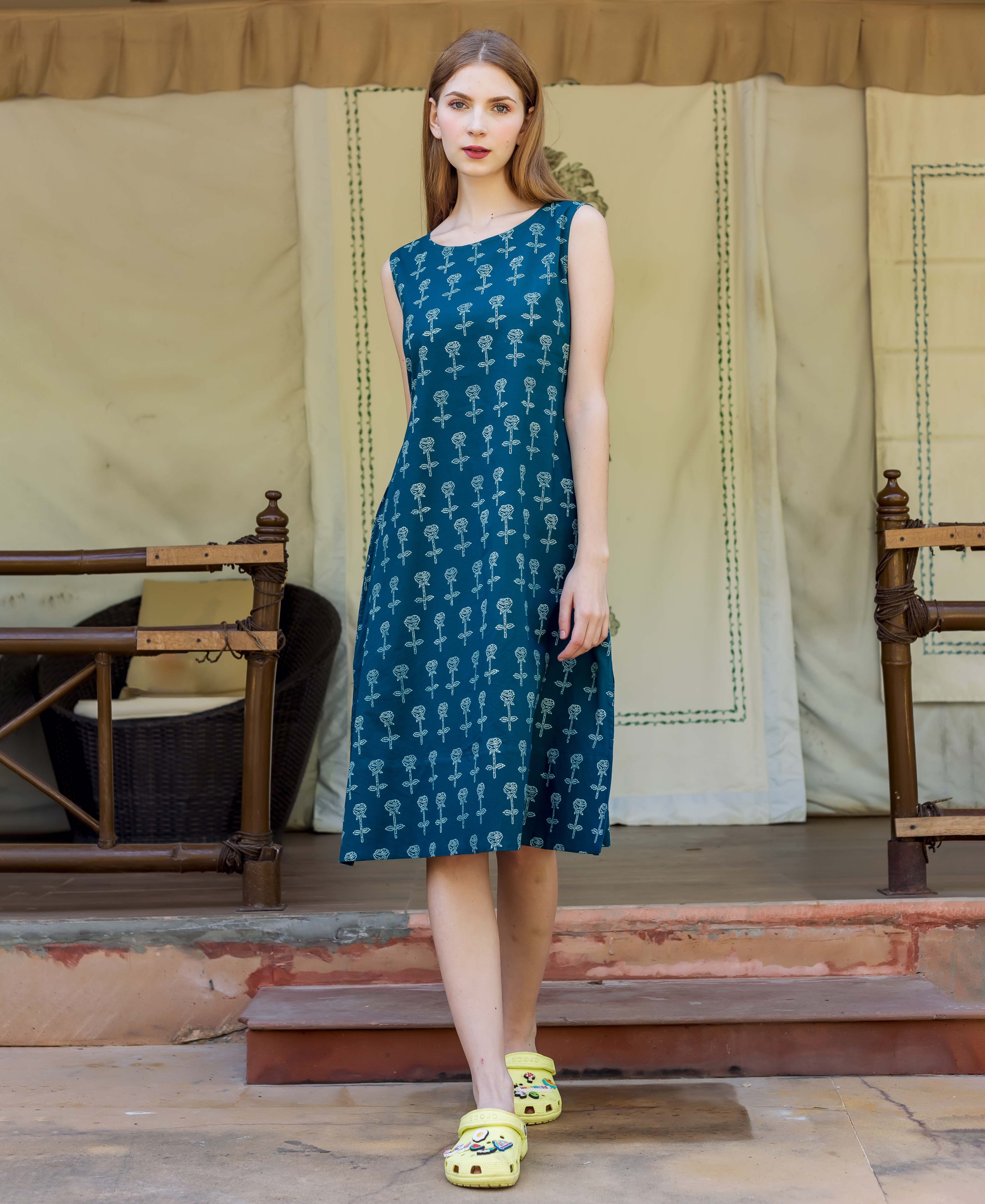 Standing model wears a teal A-line dress with small white hand-block-printed rose patterns.