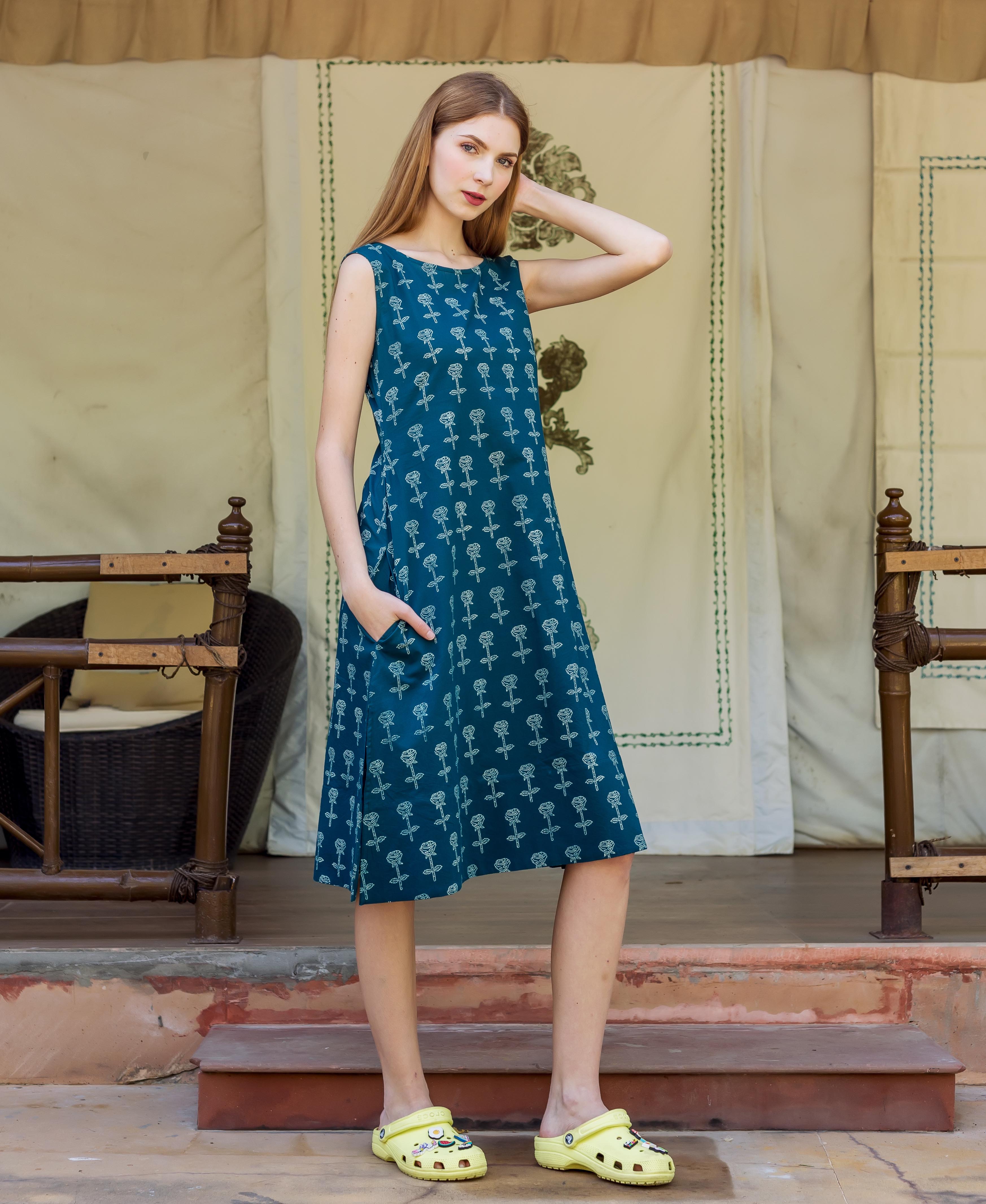 Front view of model wearing a dark teal A-line dress with white rose block print.