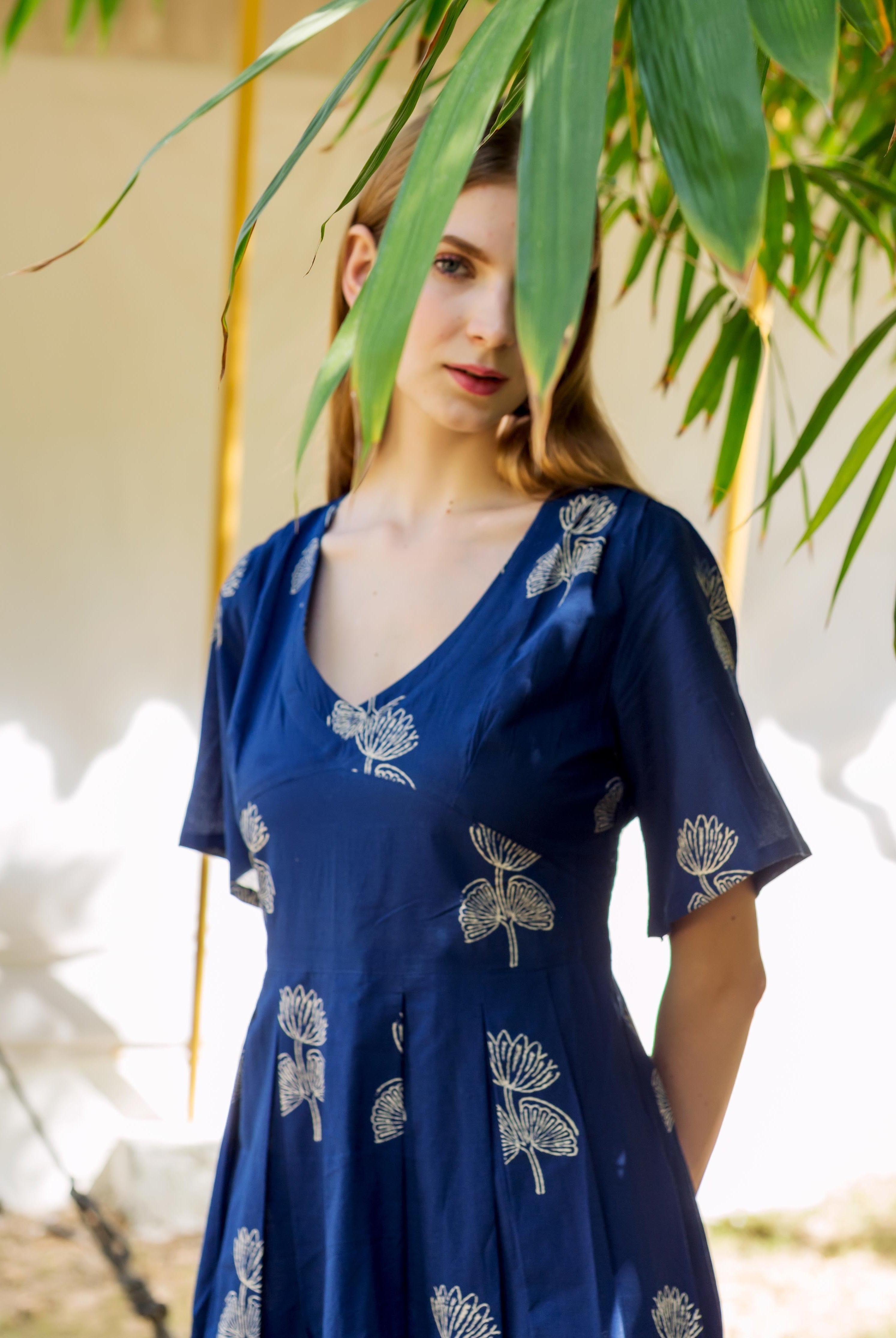 Model wears indigo blue V-neck dress with cream hand-block botanical print.