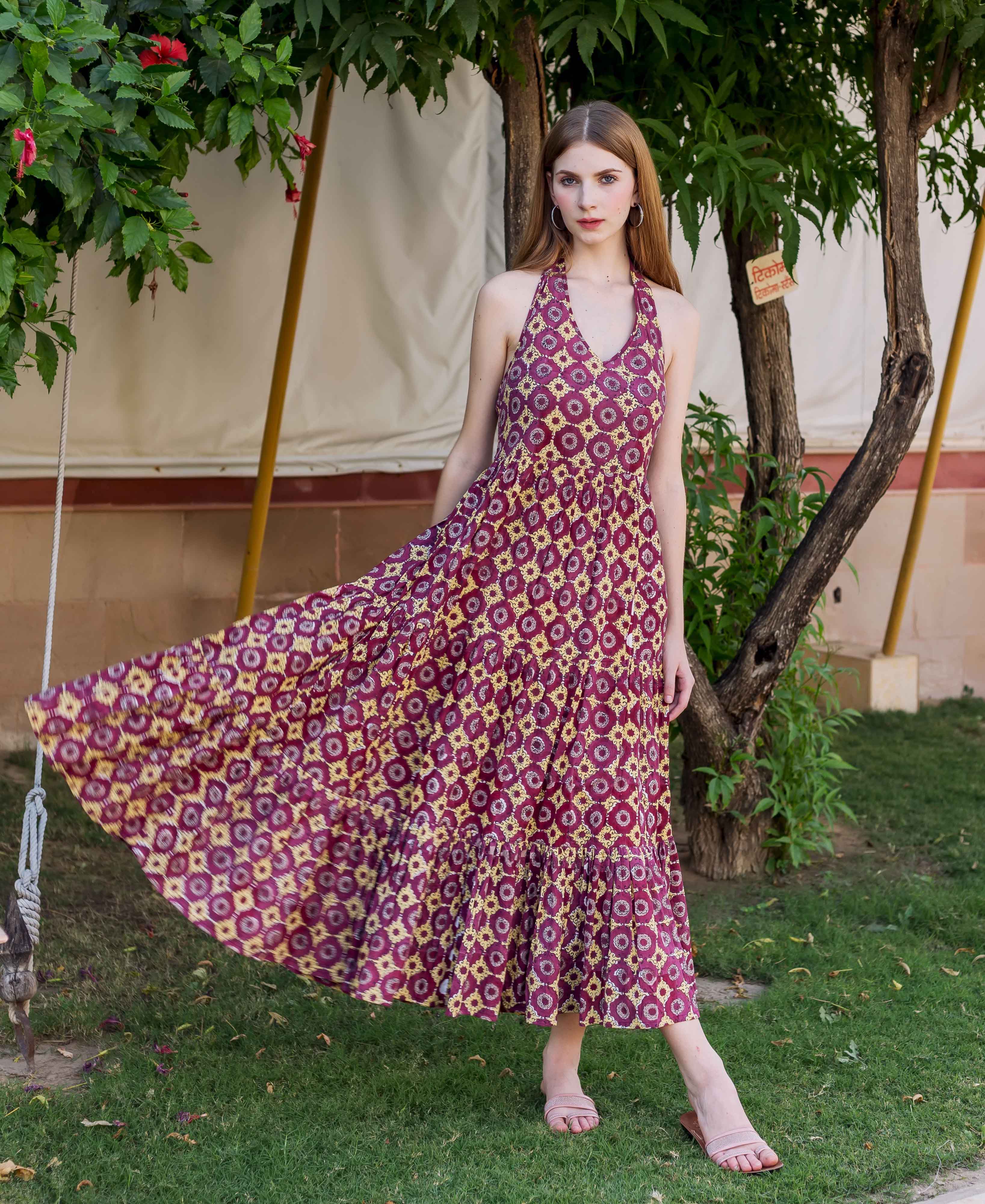 Model in a flowing wine hand-block printed halter neck maxi dress with tiered skirt.