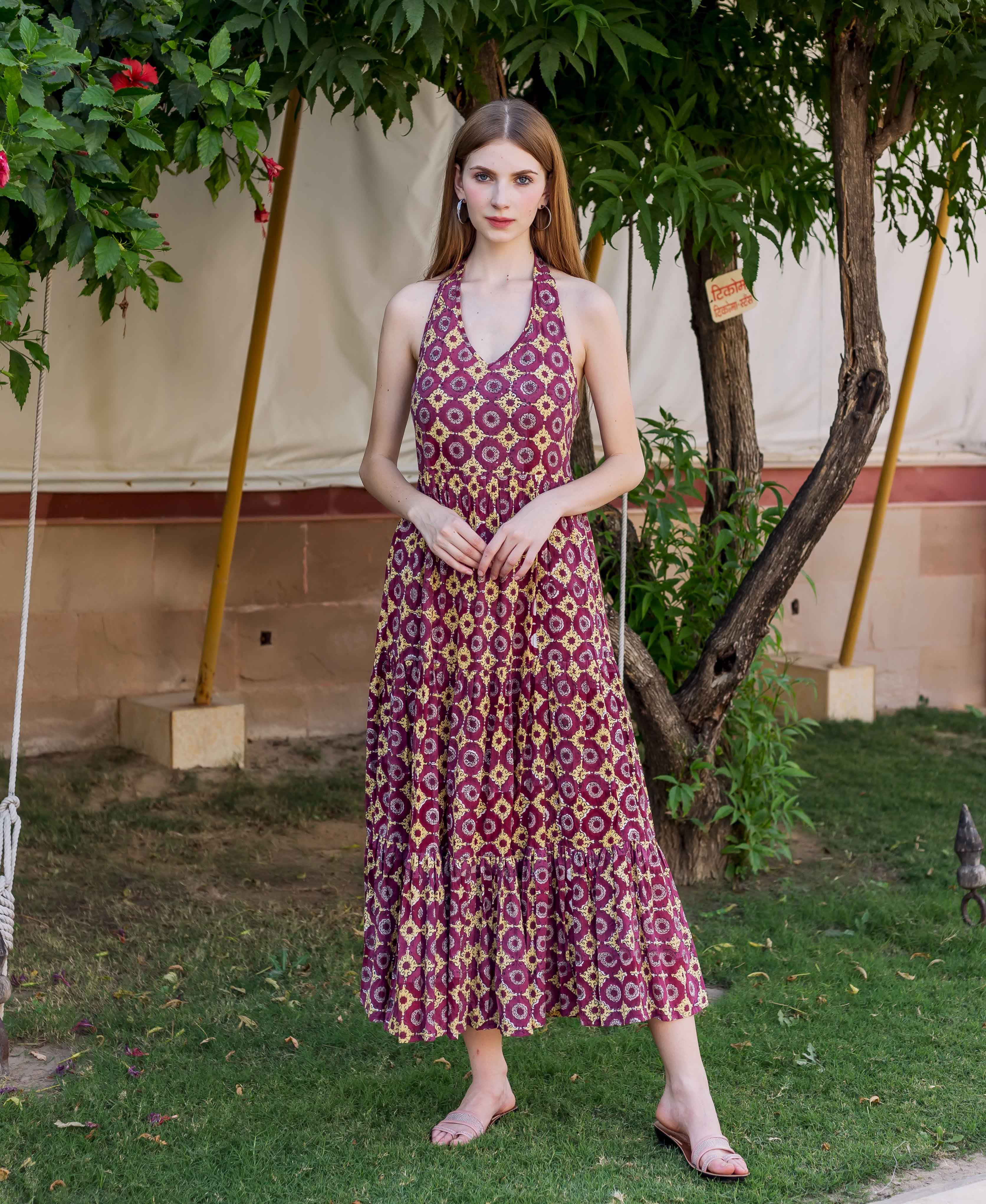Wine halter neck dress with yellow and purple hand-block-printed ethnic pattern on model outdoors.