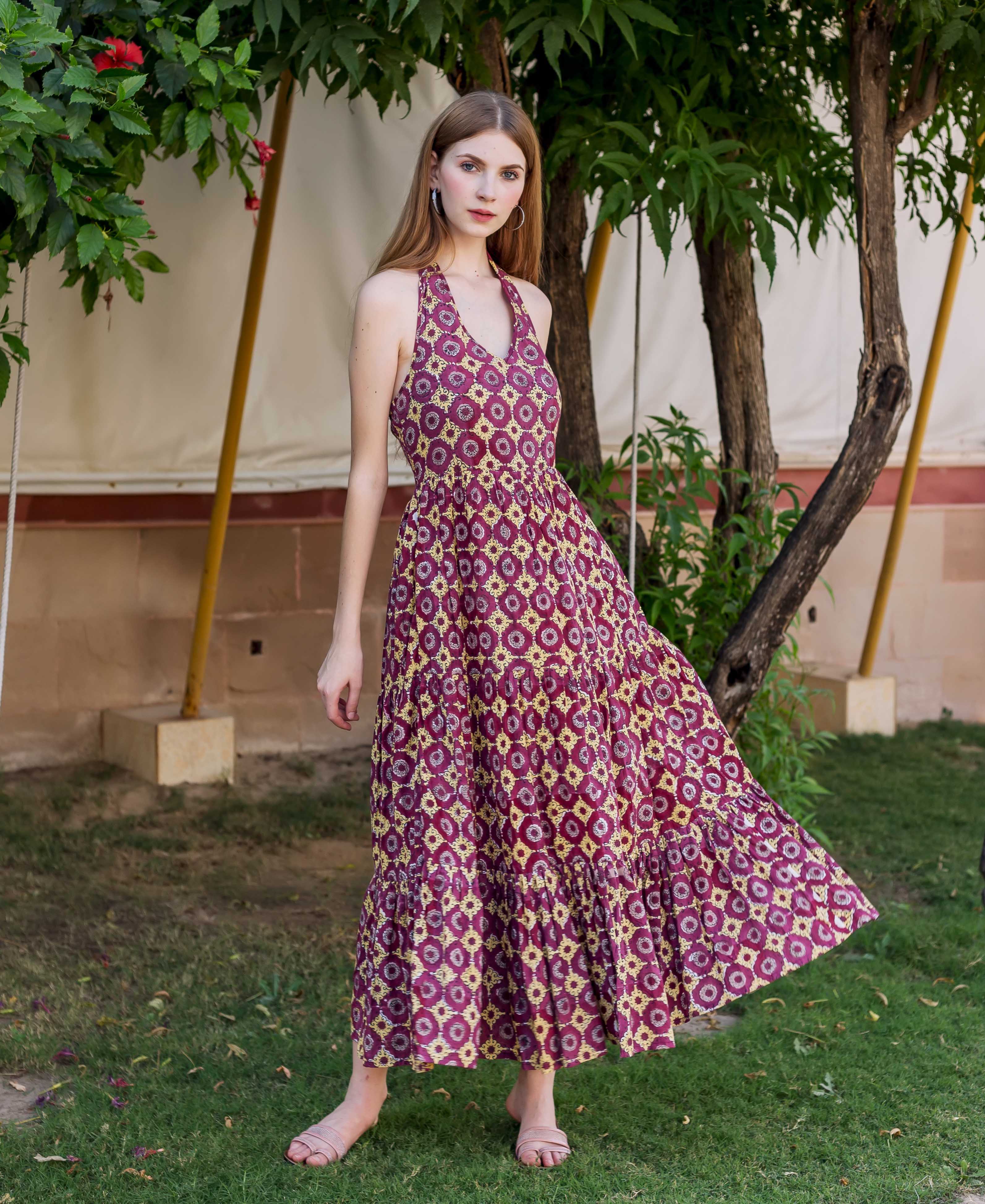 Model in a full-length wine and gold ethnic hand-block-printed tiered halter neck dress.