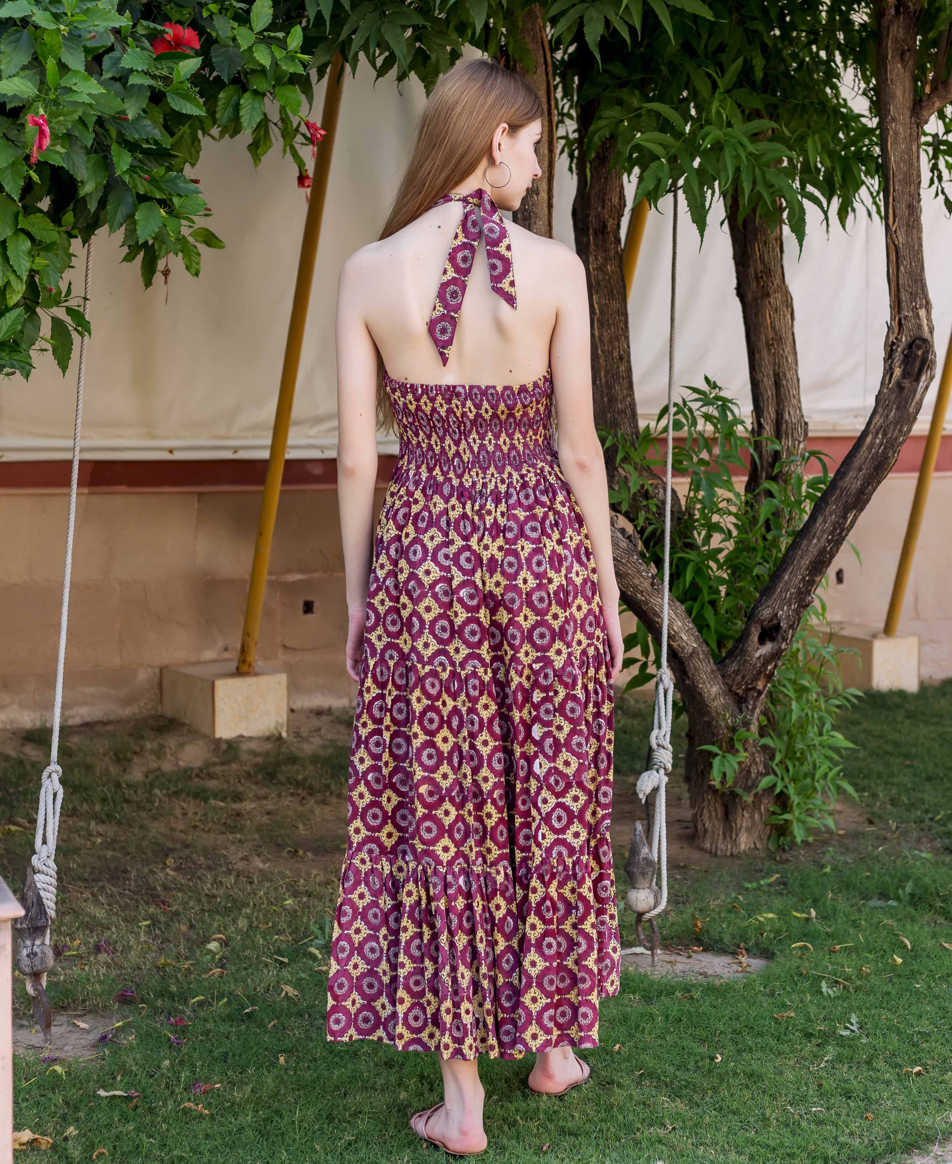 Rear view of model in wine hand-block-printed halter neck maxi dress, smocked bodice.