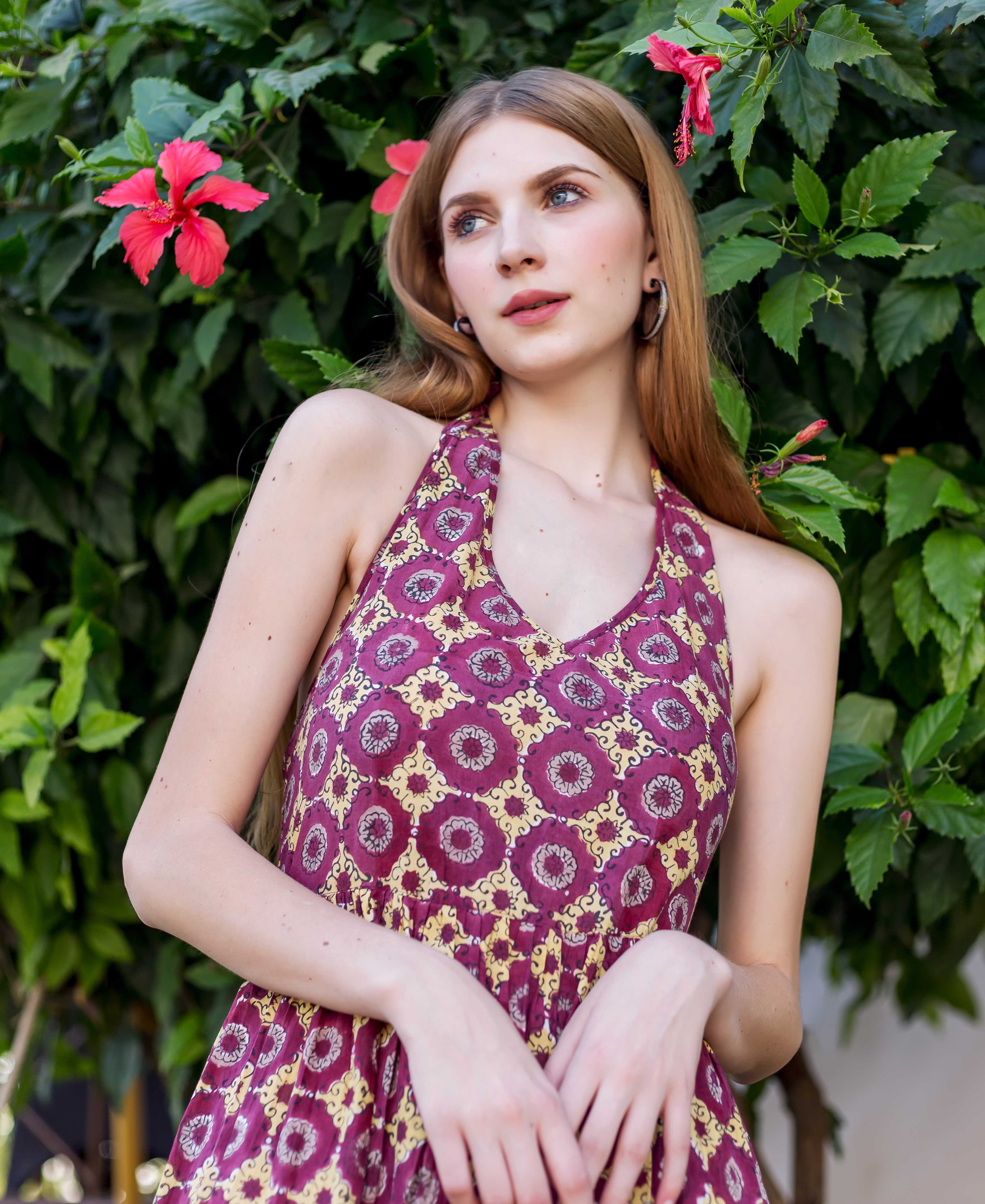 Woman wears wine halter neck dress with yellow block-printed ethnic medallions.