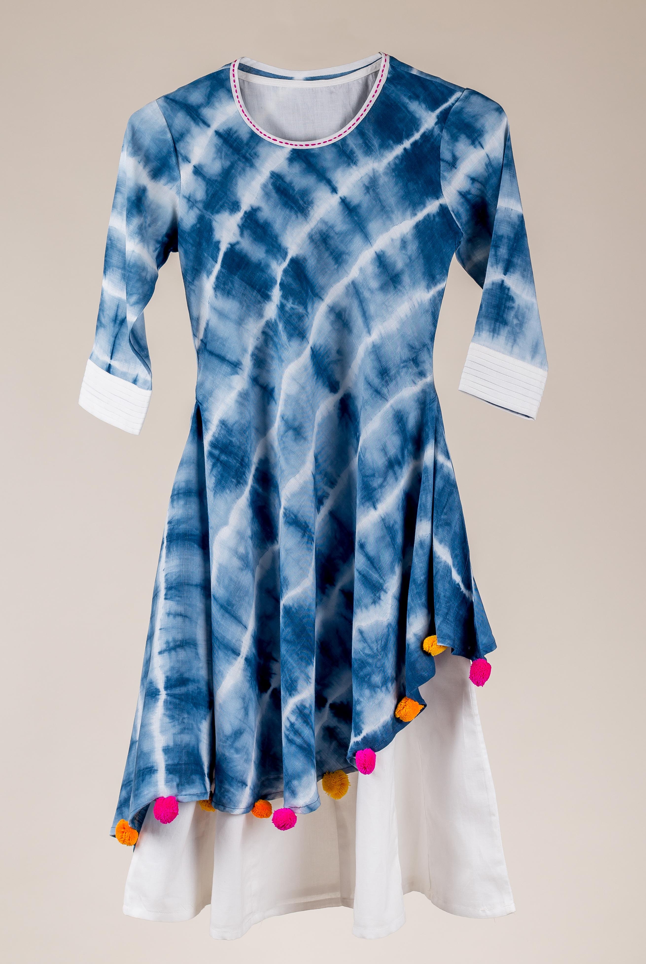 Blue and white tie-dye asymmetrical kurta dress with colorful pom-pom tassels.