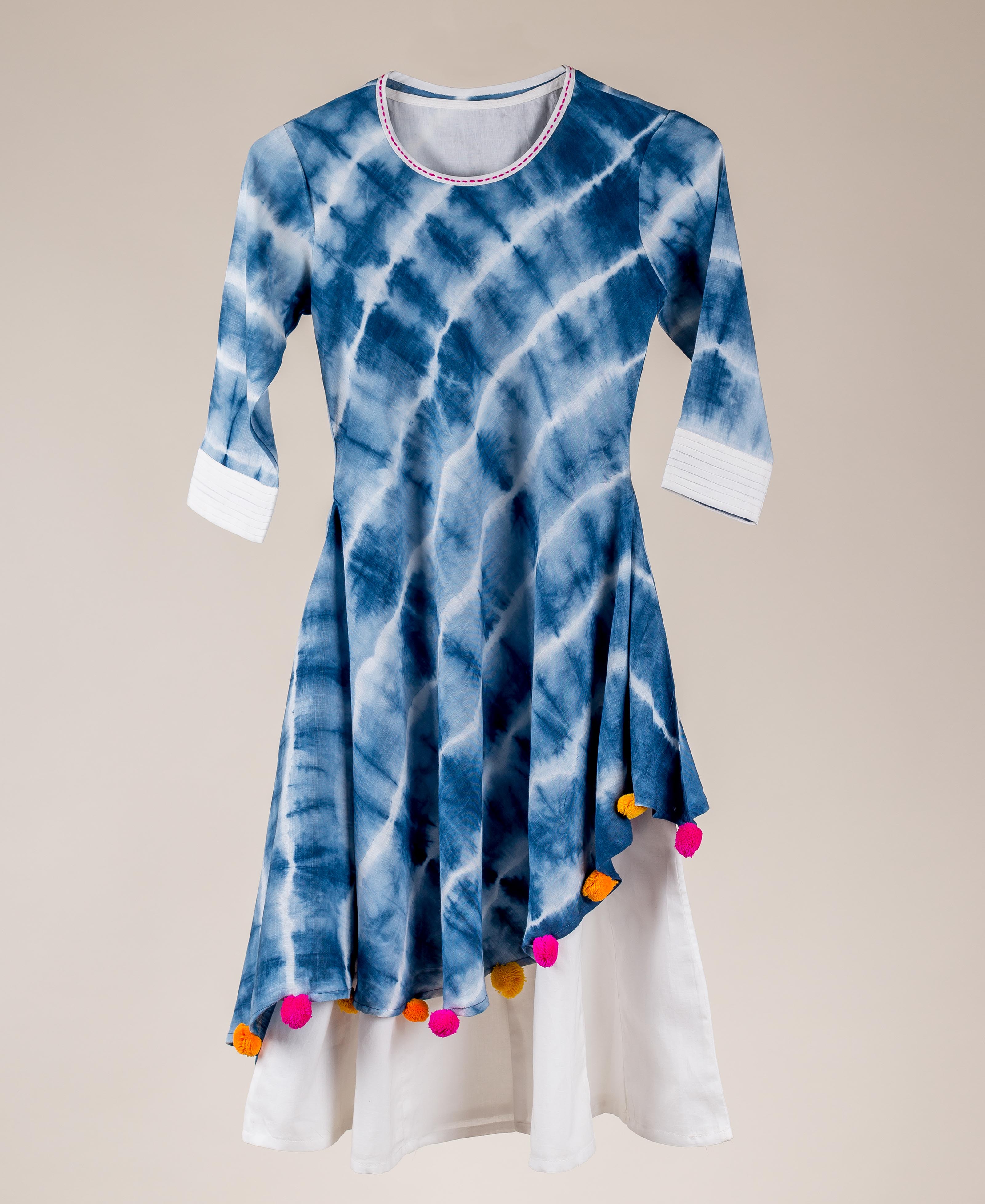 Blue and white tie-dye asymmetrical kurta dress with colorful pom-pom tassels.