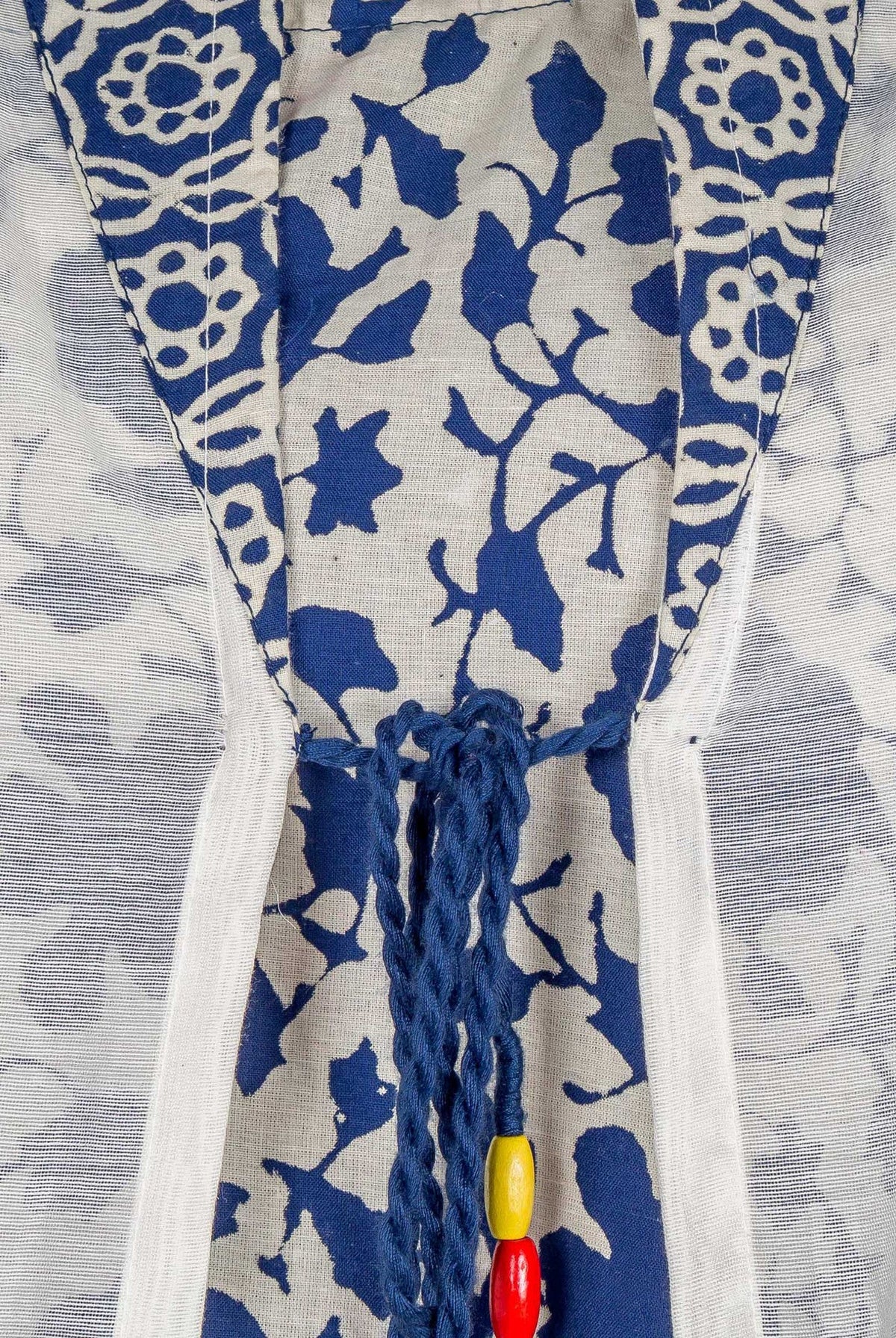 Close-up of blue and white floral hand-block-printed kurta with a decorative beaded tie.