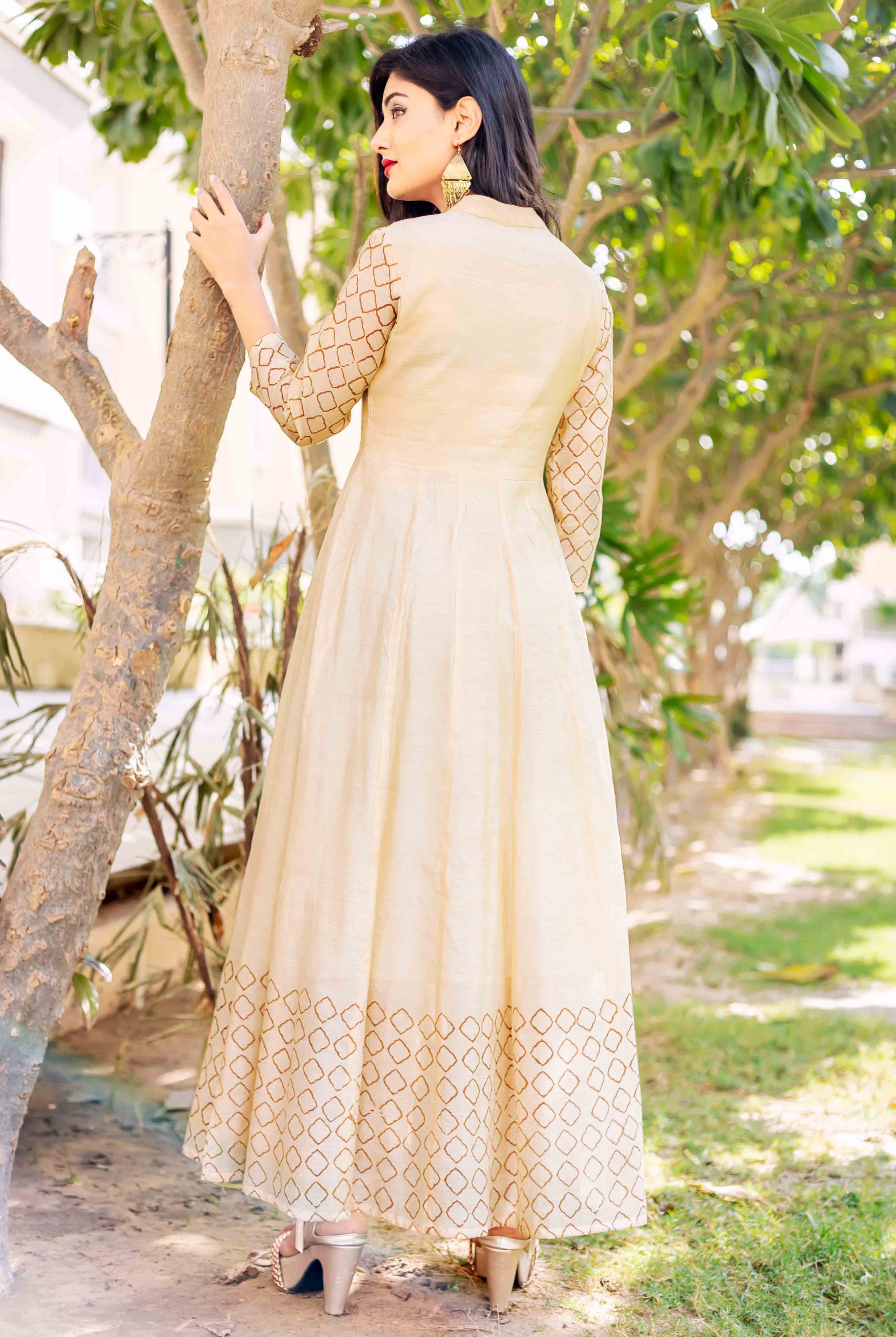Back view of a model wearing a long beige dress with brown geometric placement print.