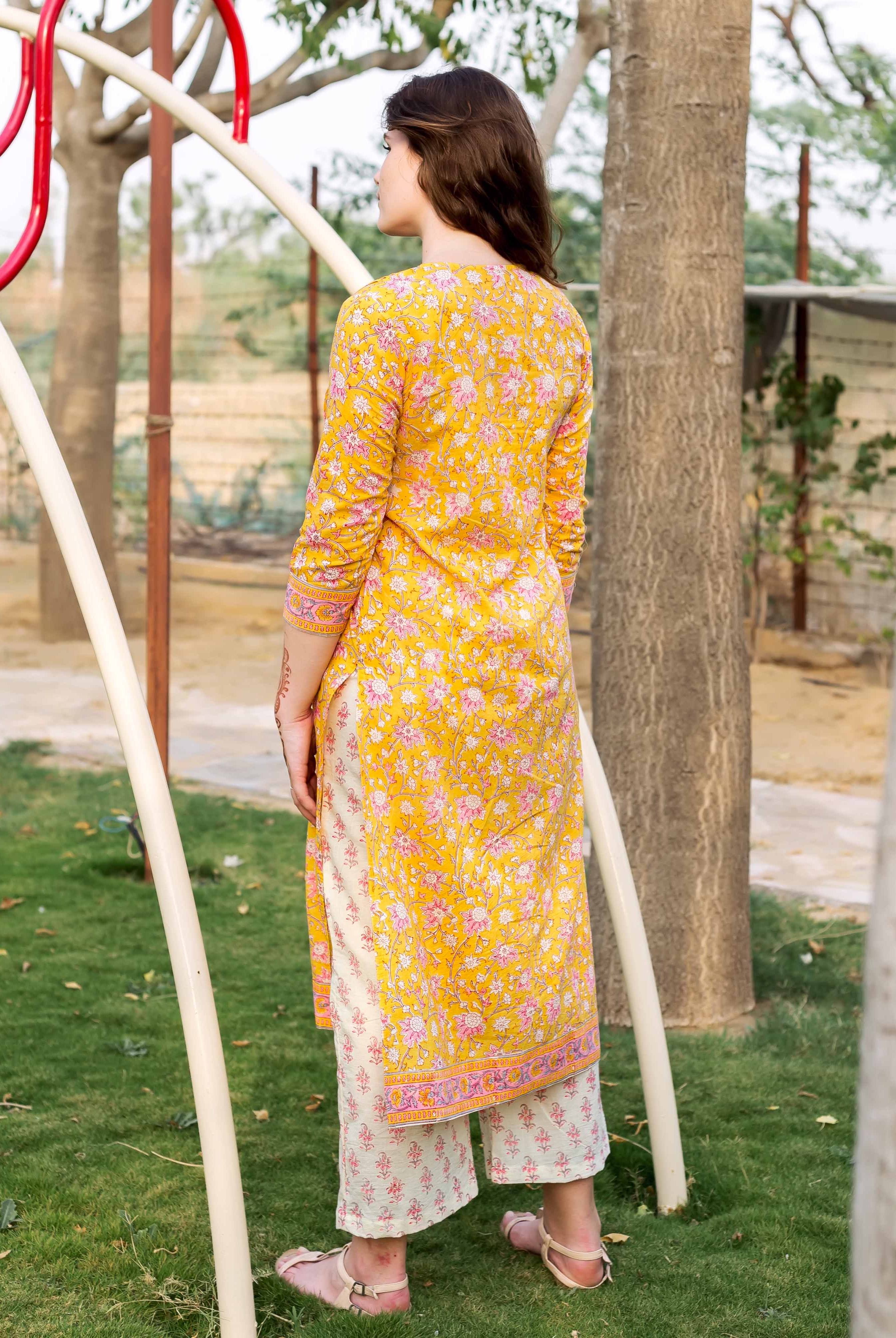 Back view of model wearing yellow floral jaal block printed straight kurta and pants.
