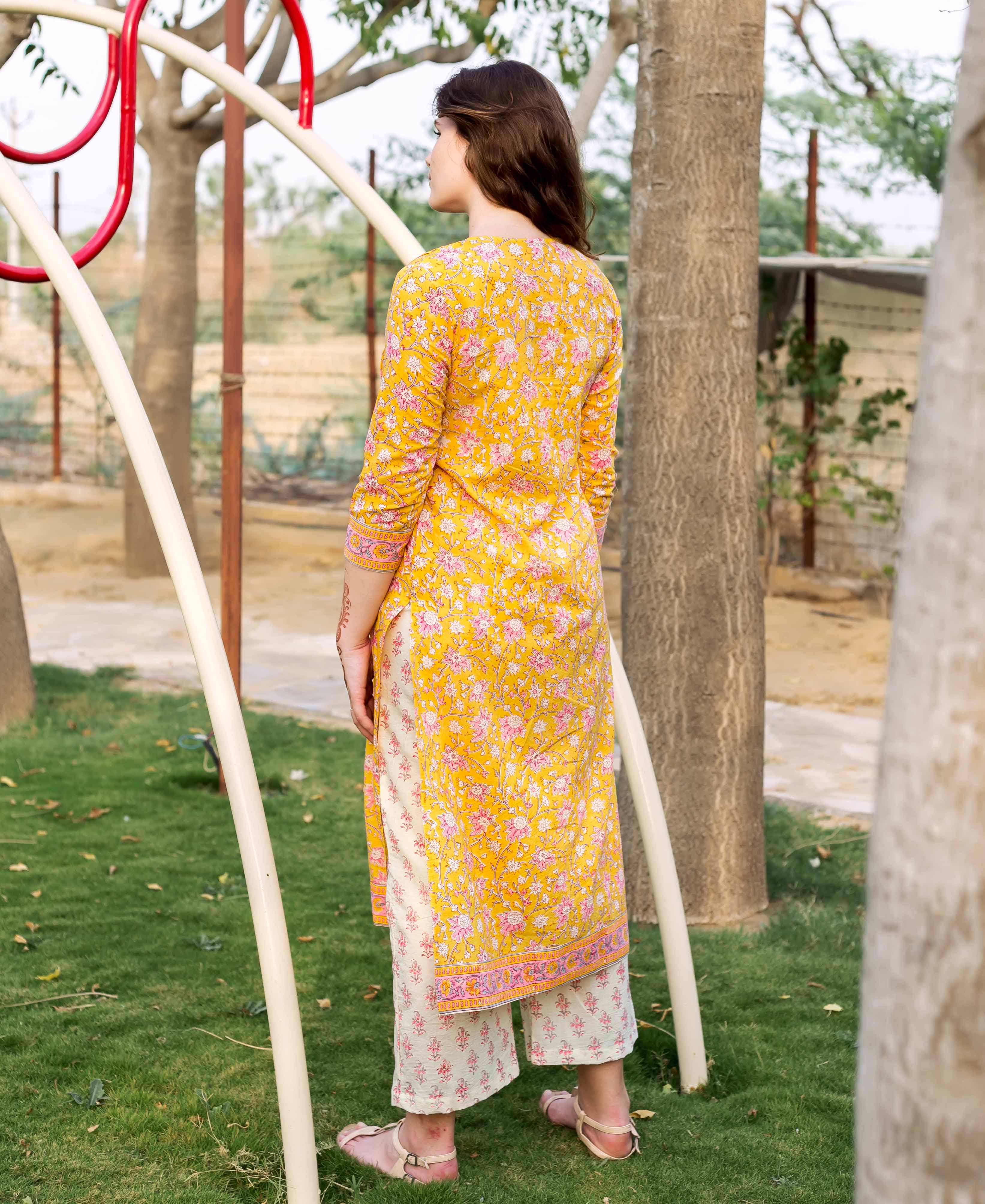 Back view of model wearing yellow floral jaal block printed straight kurta and pants.