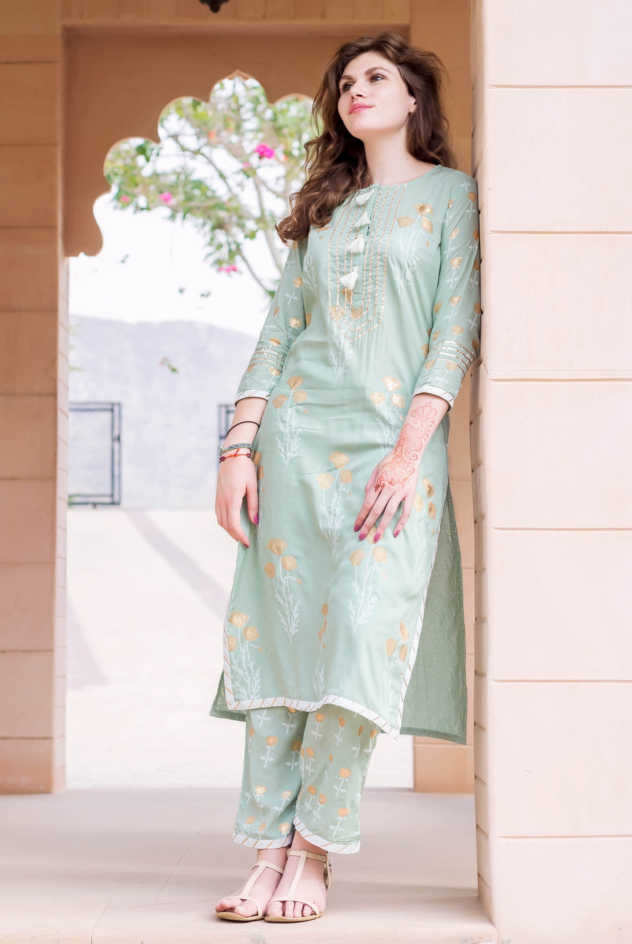 Model in a mint green hand-block-printed cotton kurta set with golden floral designs.