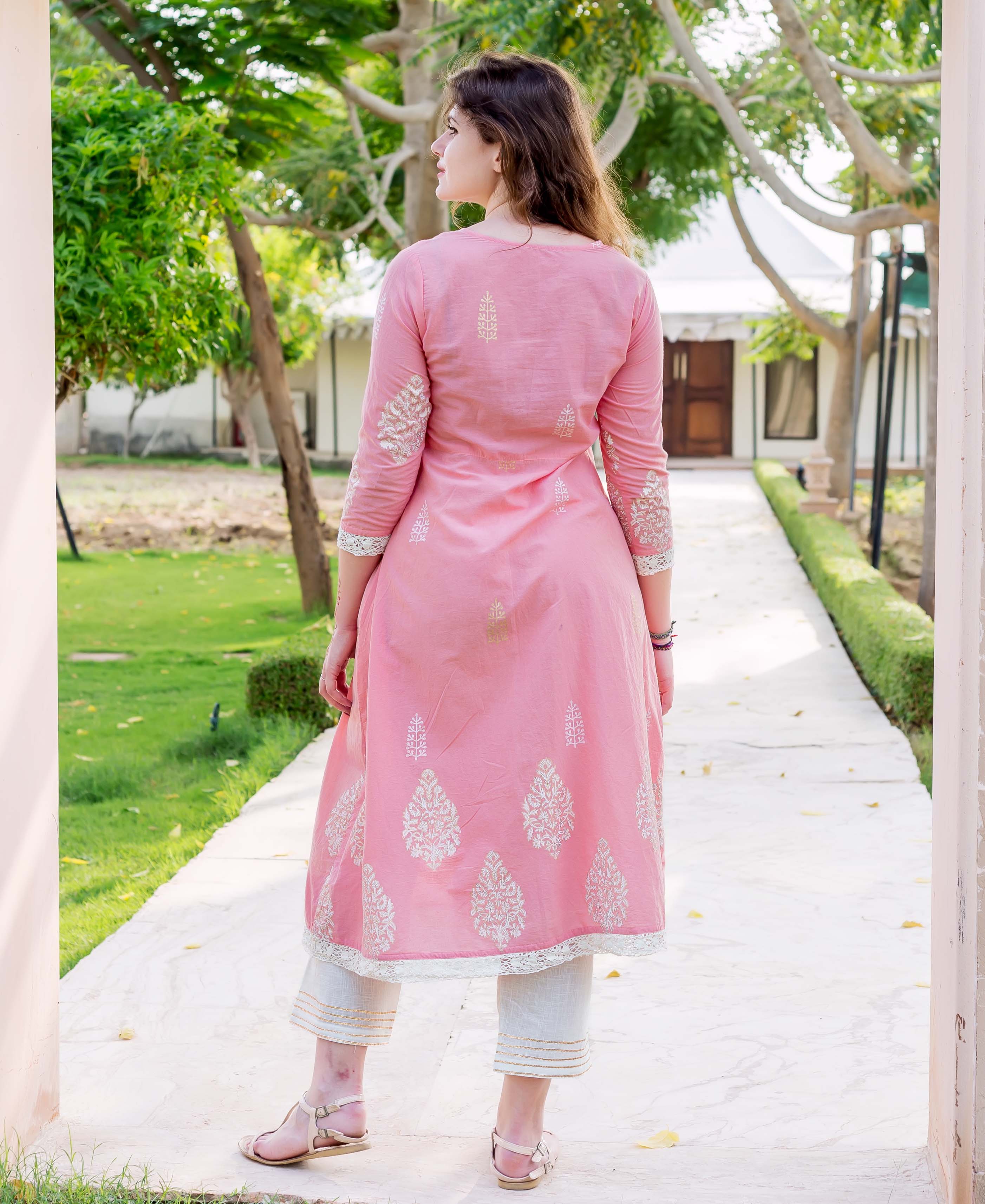 Back view of model in pink A-line hand-block-printed kurta with white leaf motifs and light trousers.