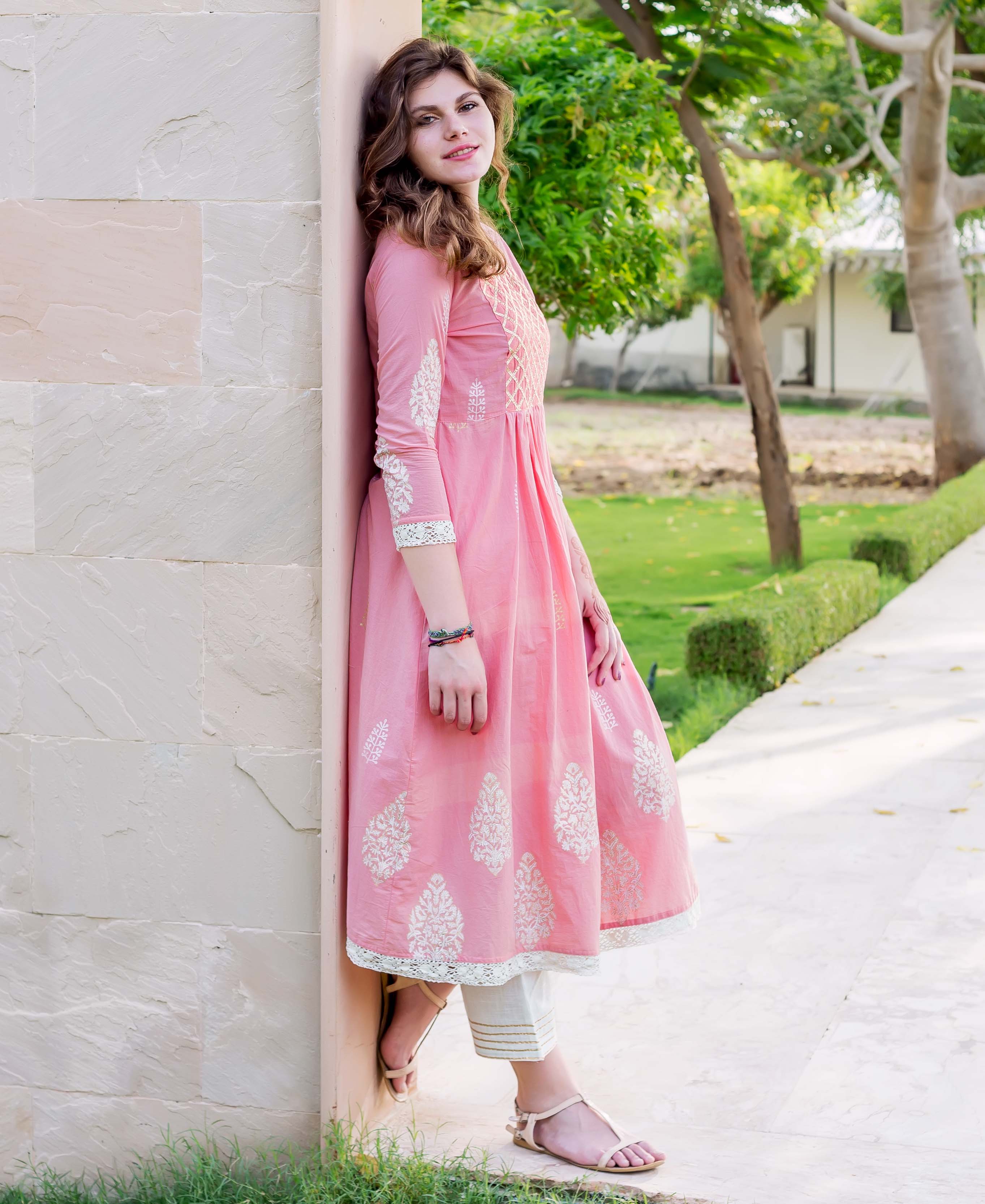 Side view of model in pink A-line hand-block printed kurta and white bottoms.