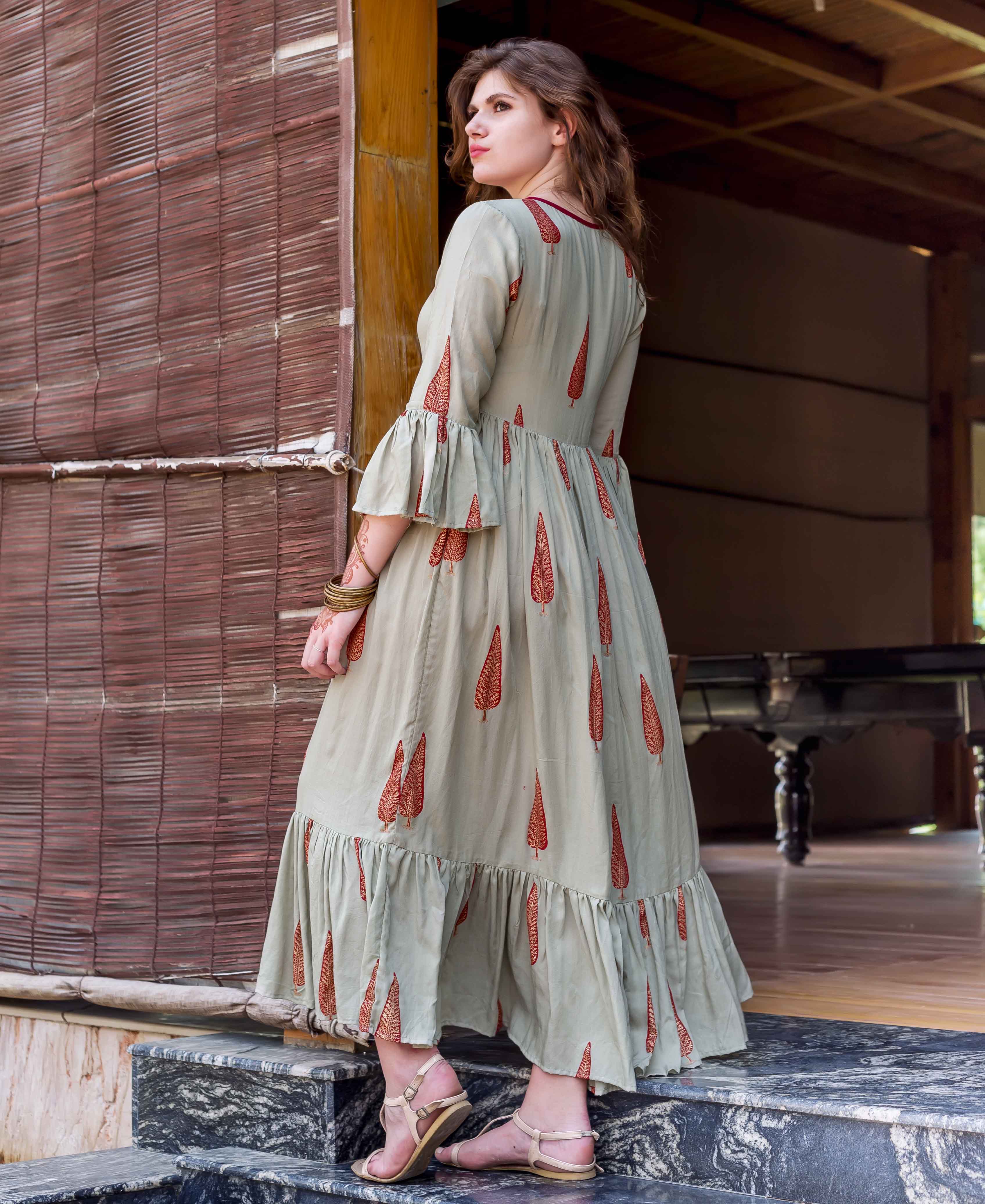 Model in sage green rayon block printed long dress with red leaf design and ruffles.