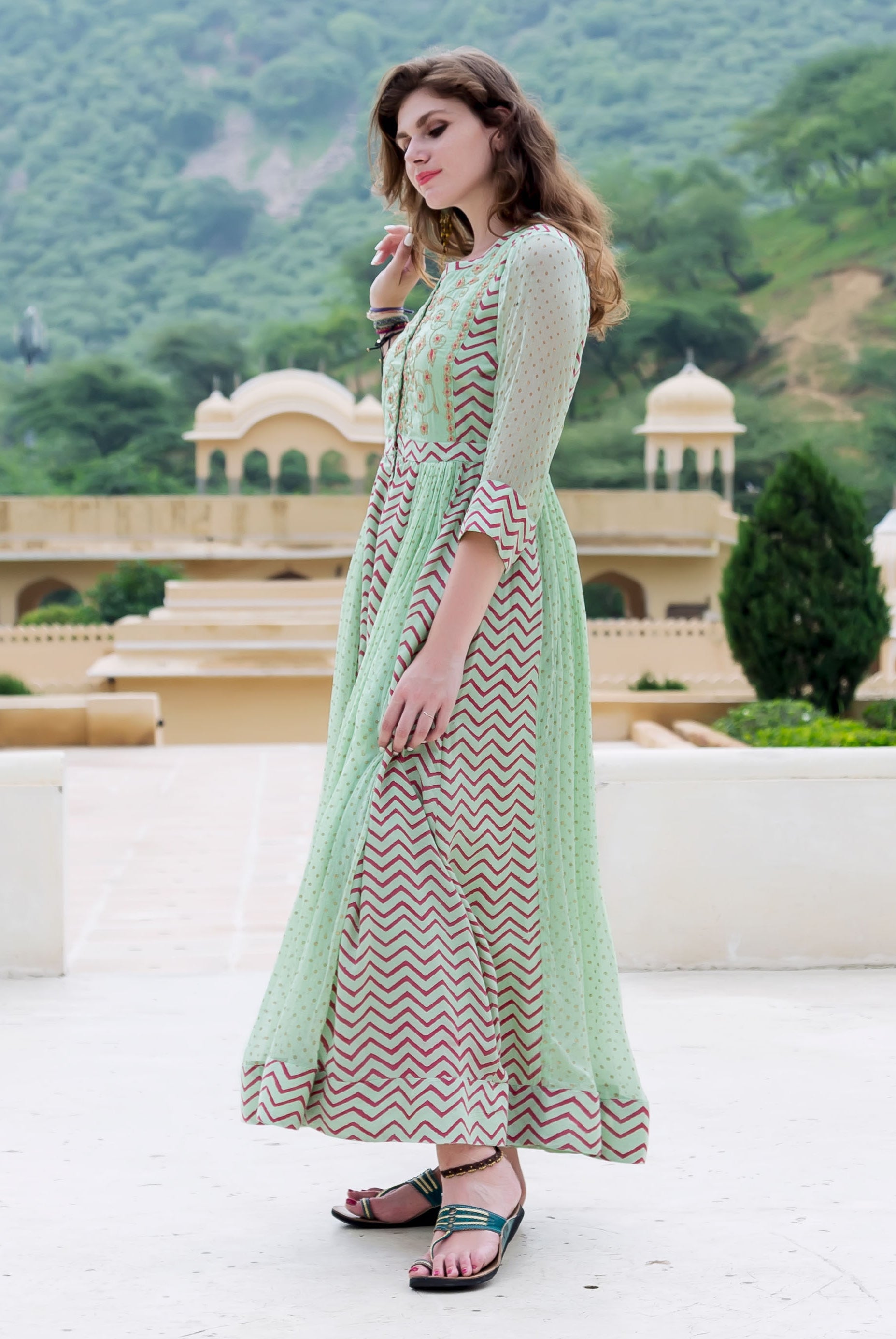 Full-length side view of model in mint green chiffon Anarkali dress with block printed chevron and dots.