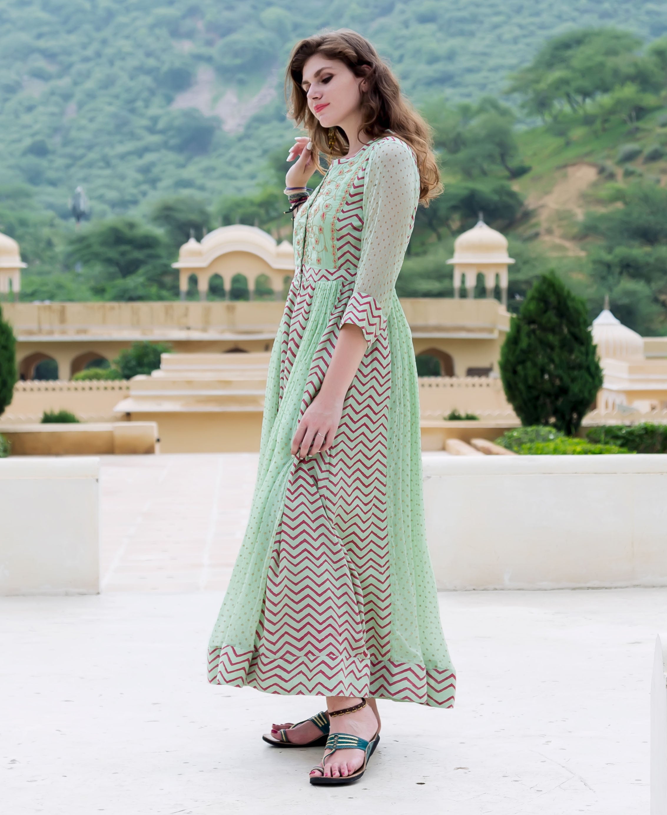 Full-length side view of model in mint green chiffon Anarkali dress with block printed chevron and dots.