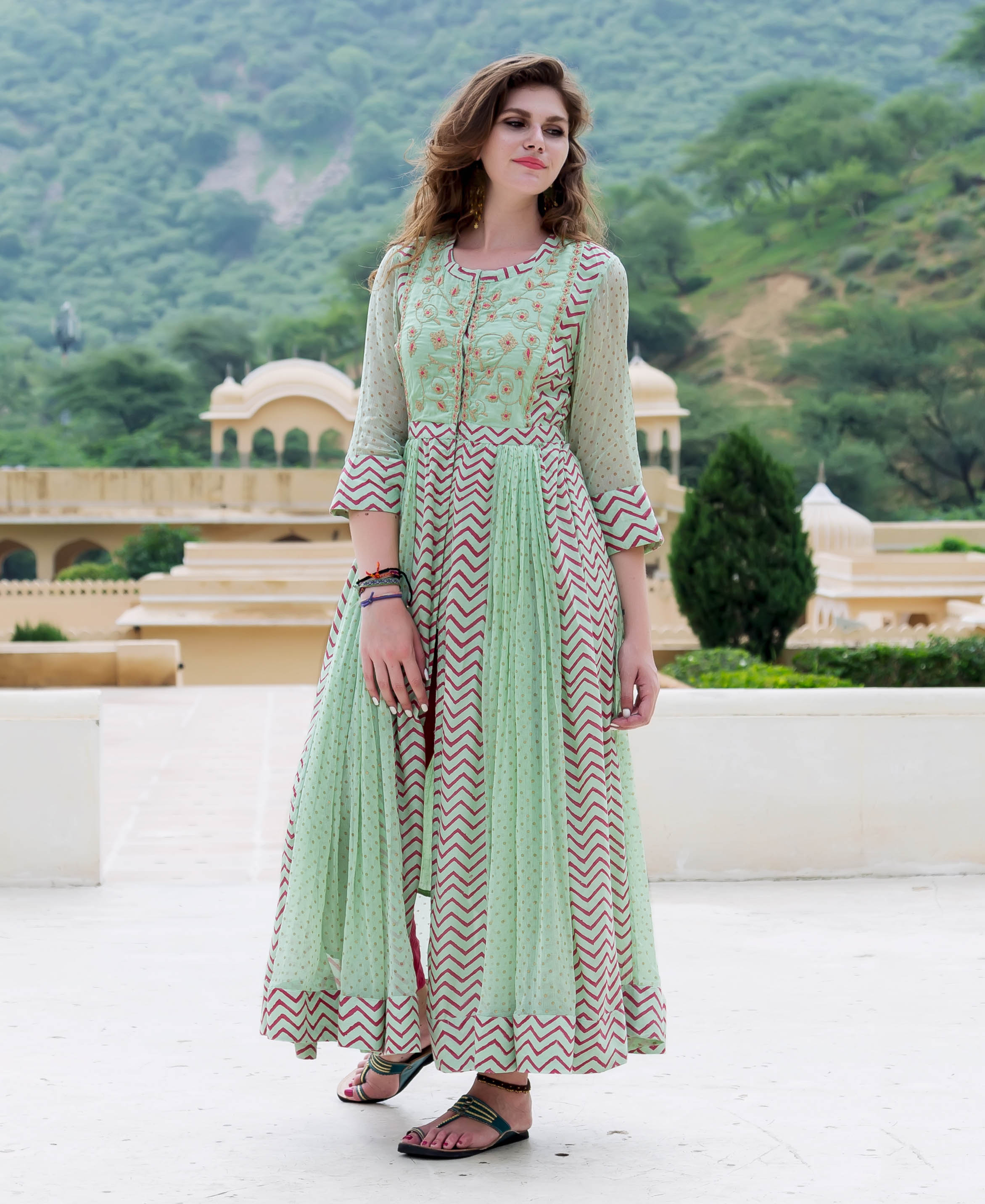 Model wears mint green chiffon anarkali with embroidered bodice and red zig-zag print.