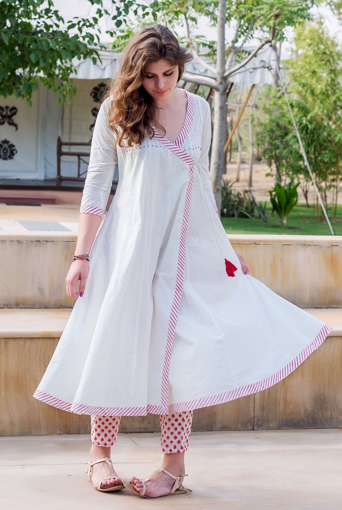 Woman in white angrakha dress with red striped trim and red block-printed pants.