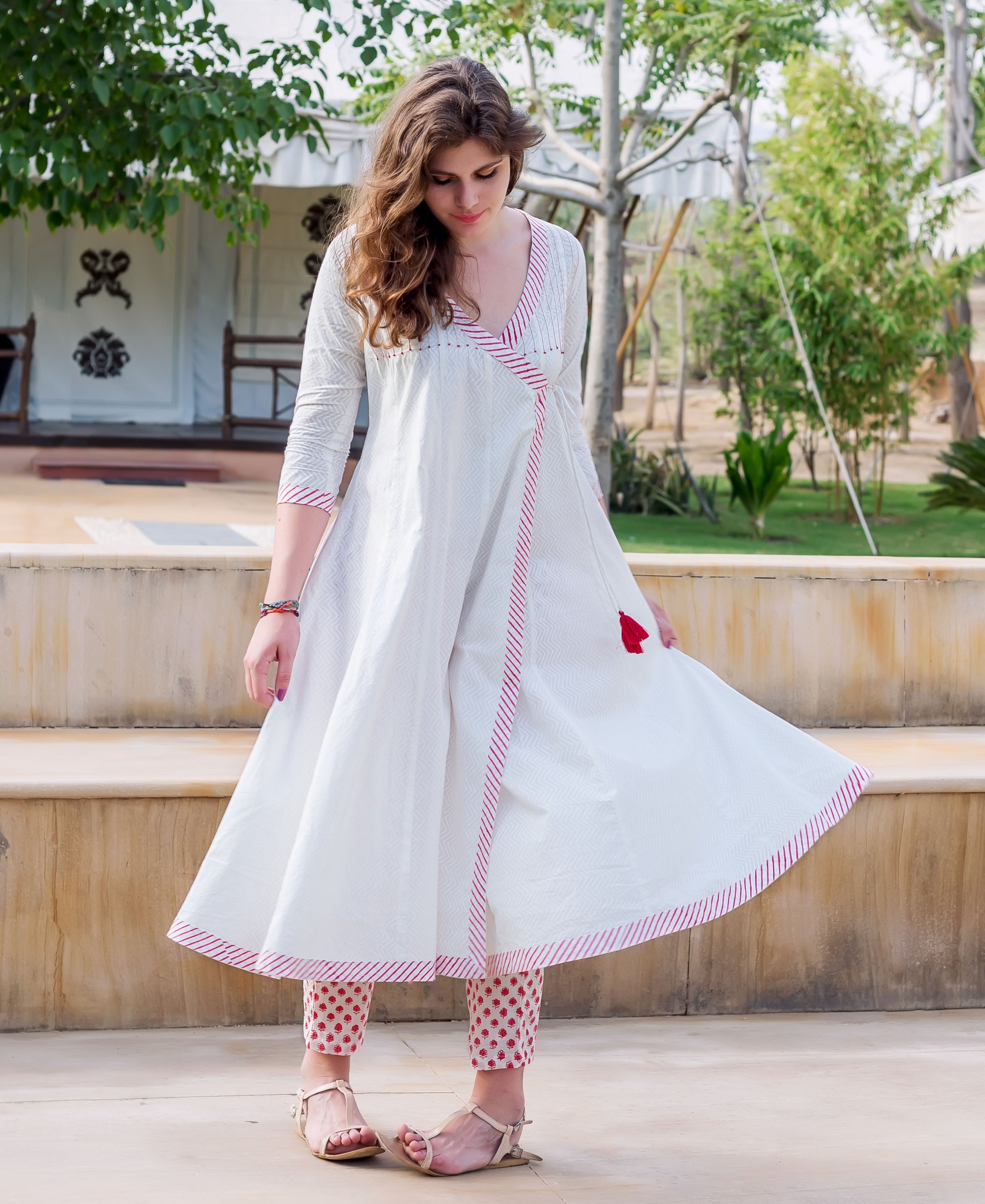 Woman in white angrakha dress with red striped trim and red block-printed pants.