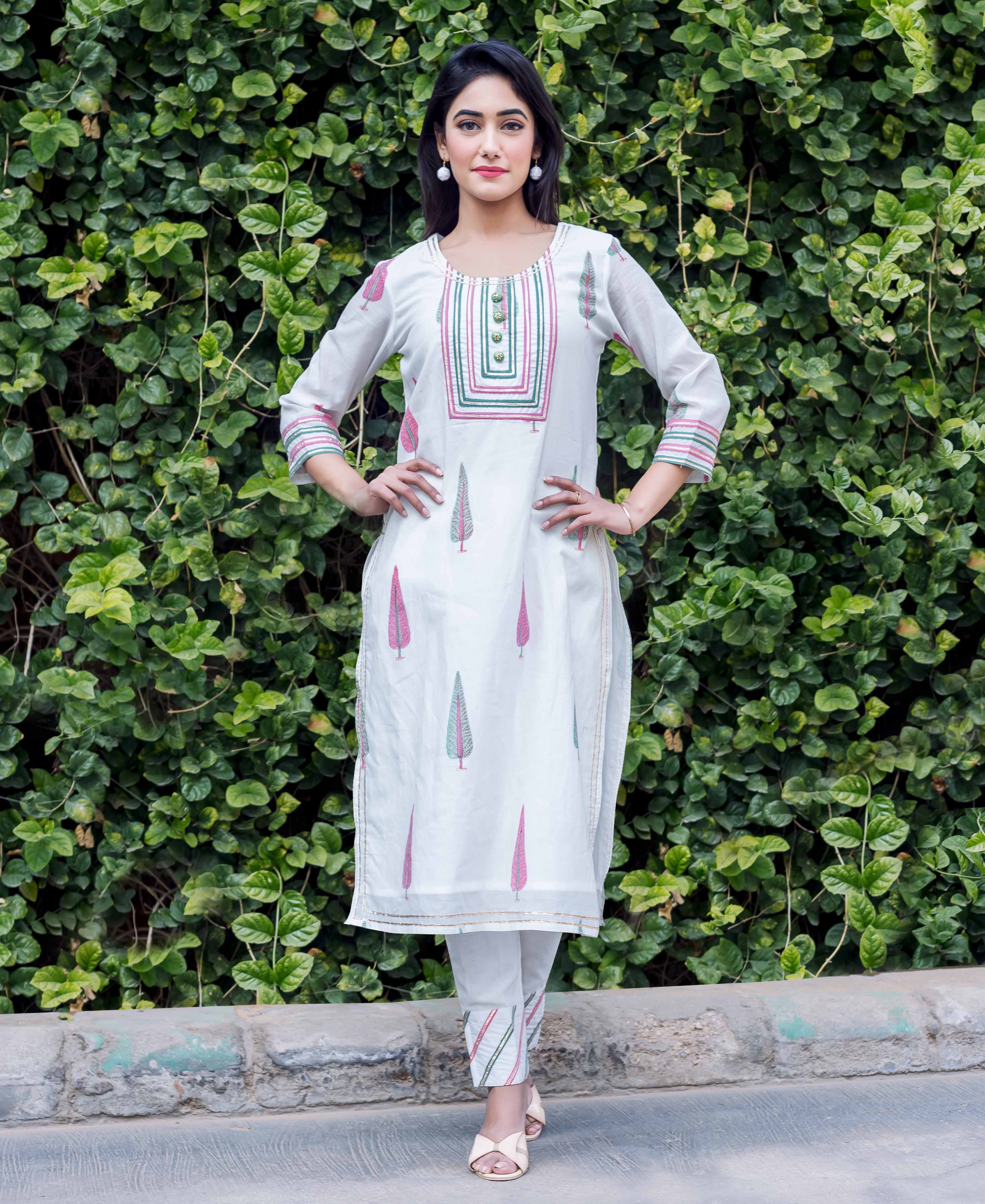 Woman in white chanderi block printed kurta with pink and green trees and embroidery details.