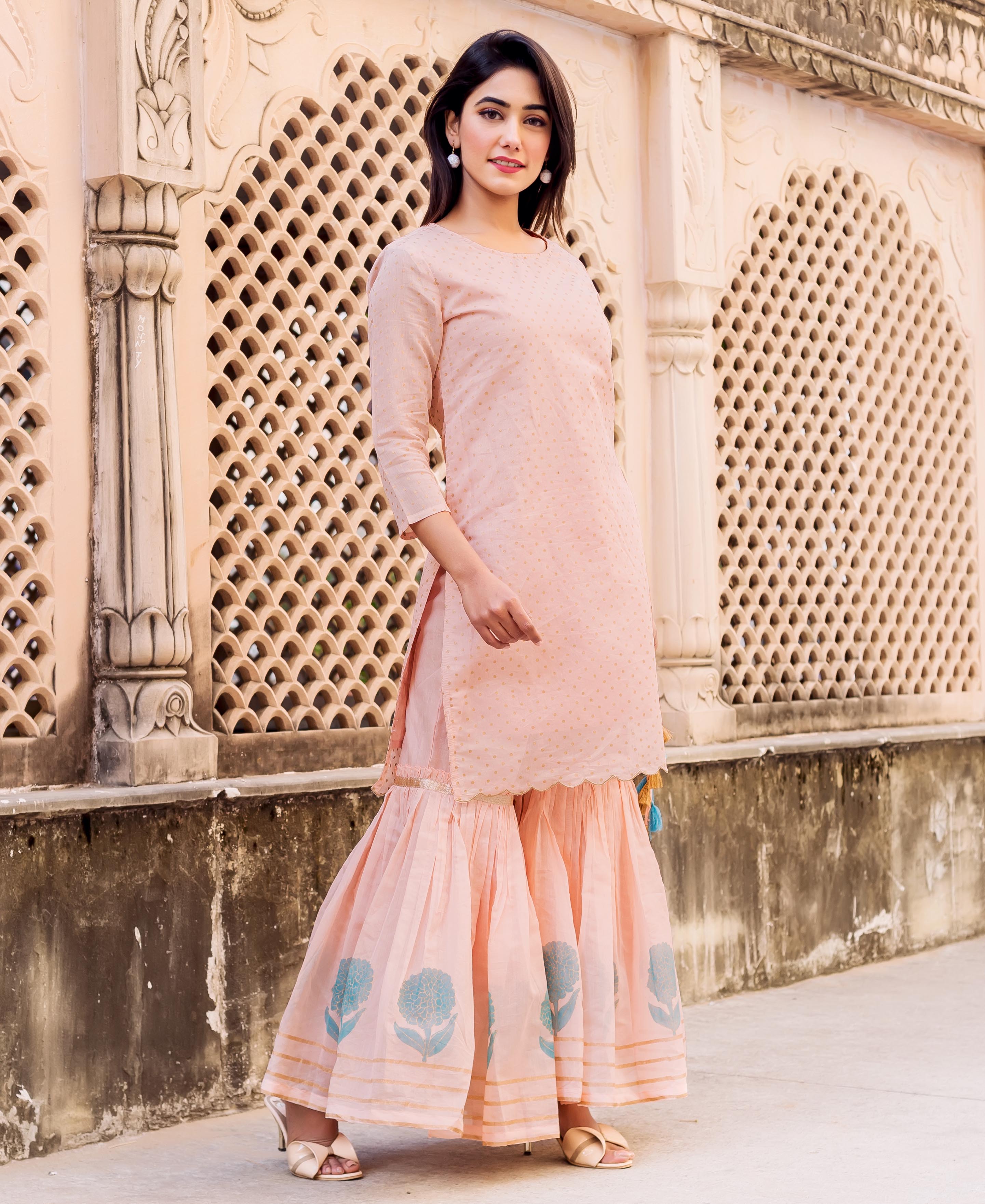 Model wearing a peach polka dot kurta and tiered gharara with blue floral hand-block print.