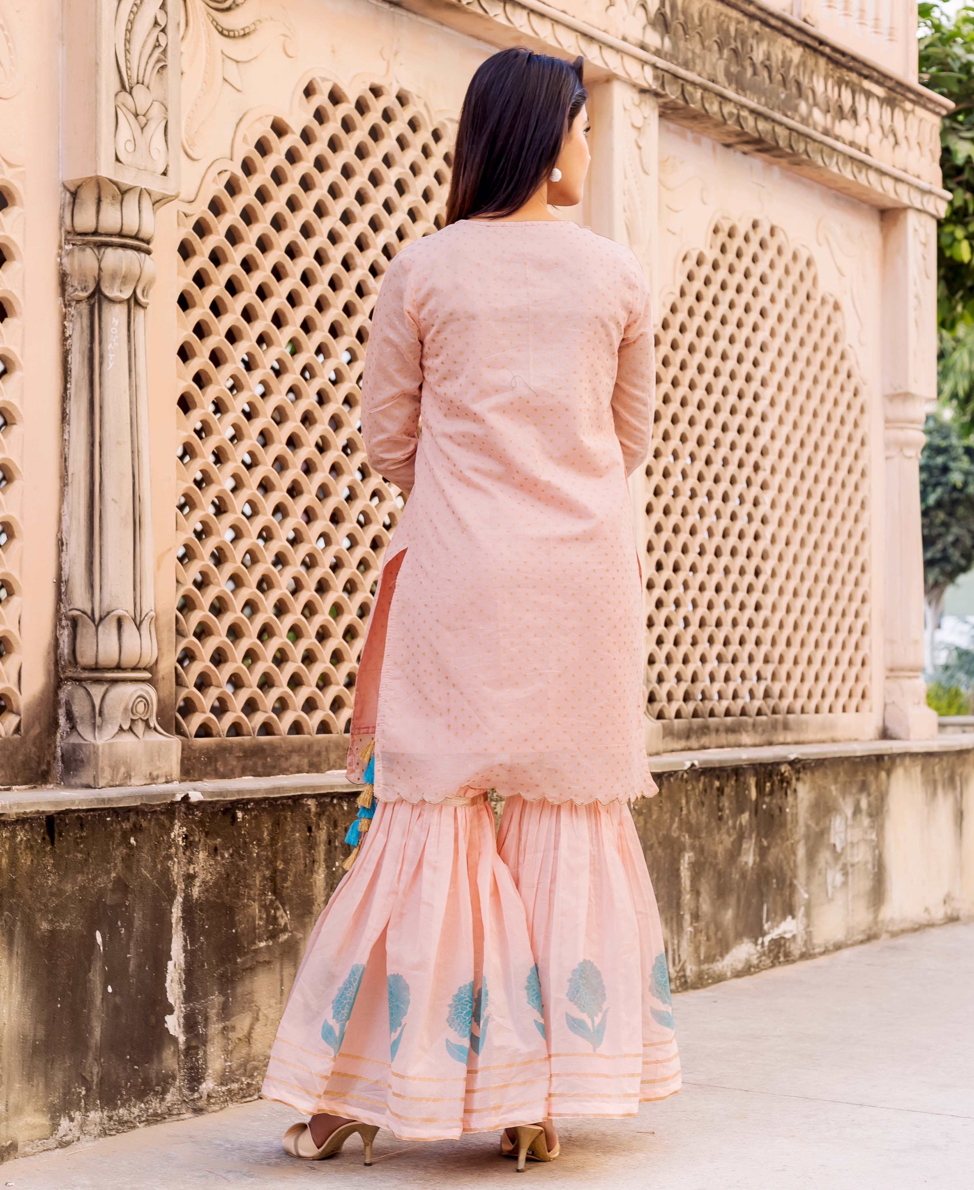 Model from back, peach polka printed and embroidered kurta with block-printed sharara.