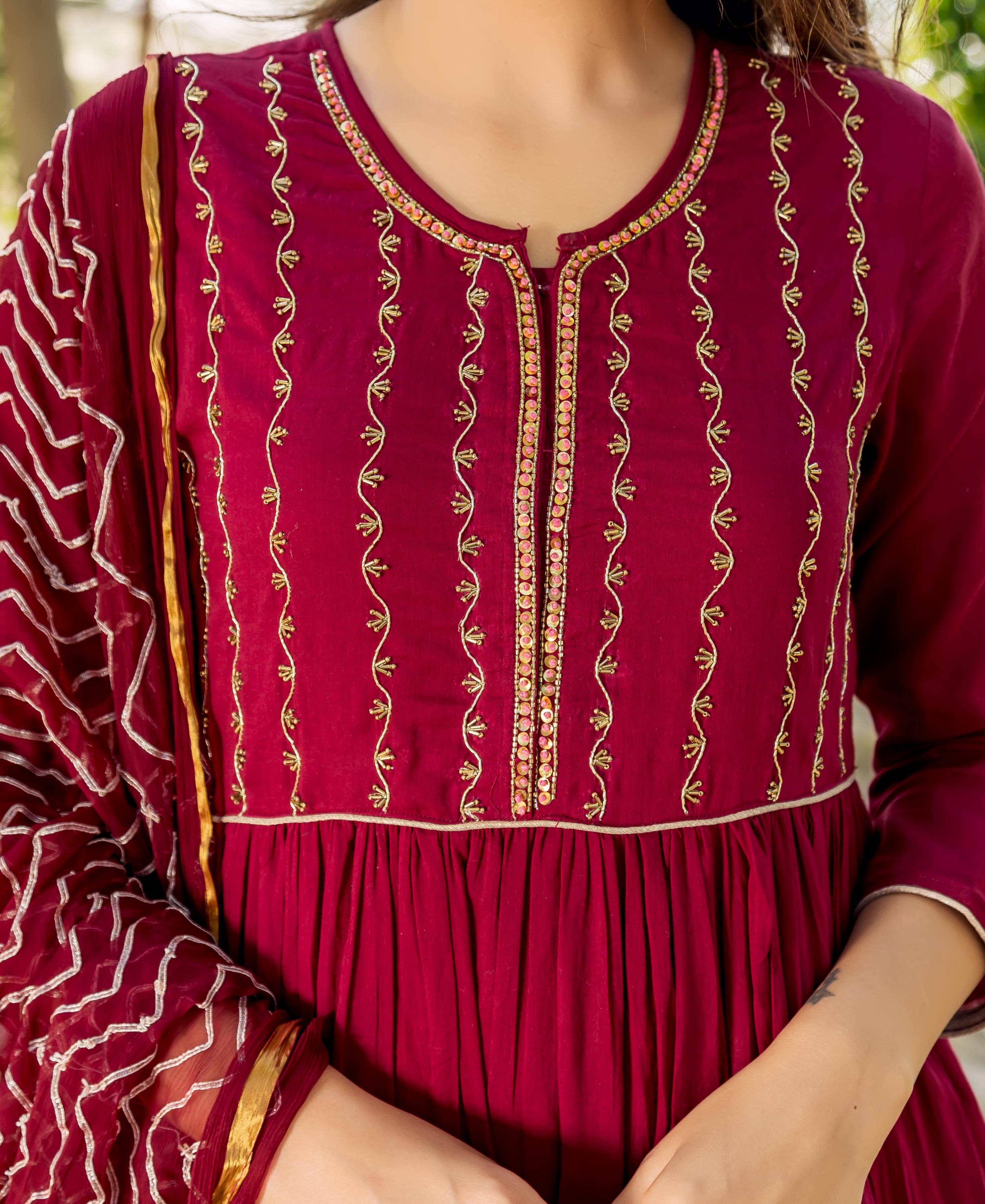 Maroon tiered dress with intricate gold hand embroidery on the yoke, worn by a model.