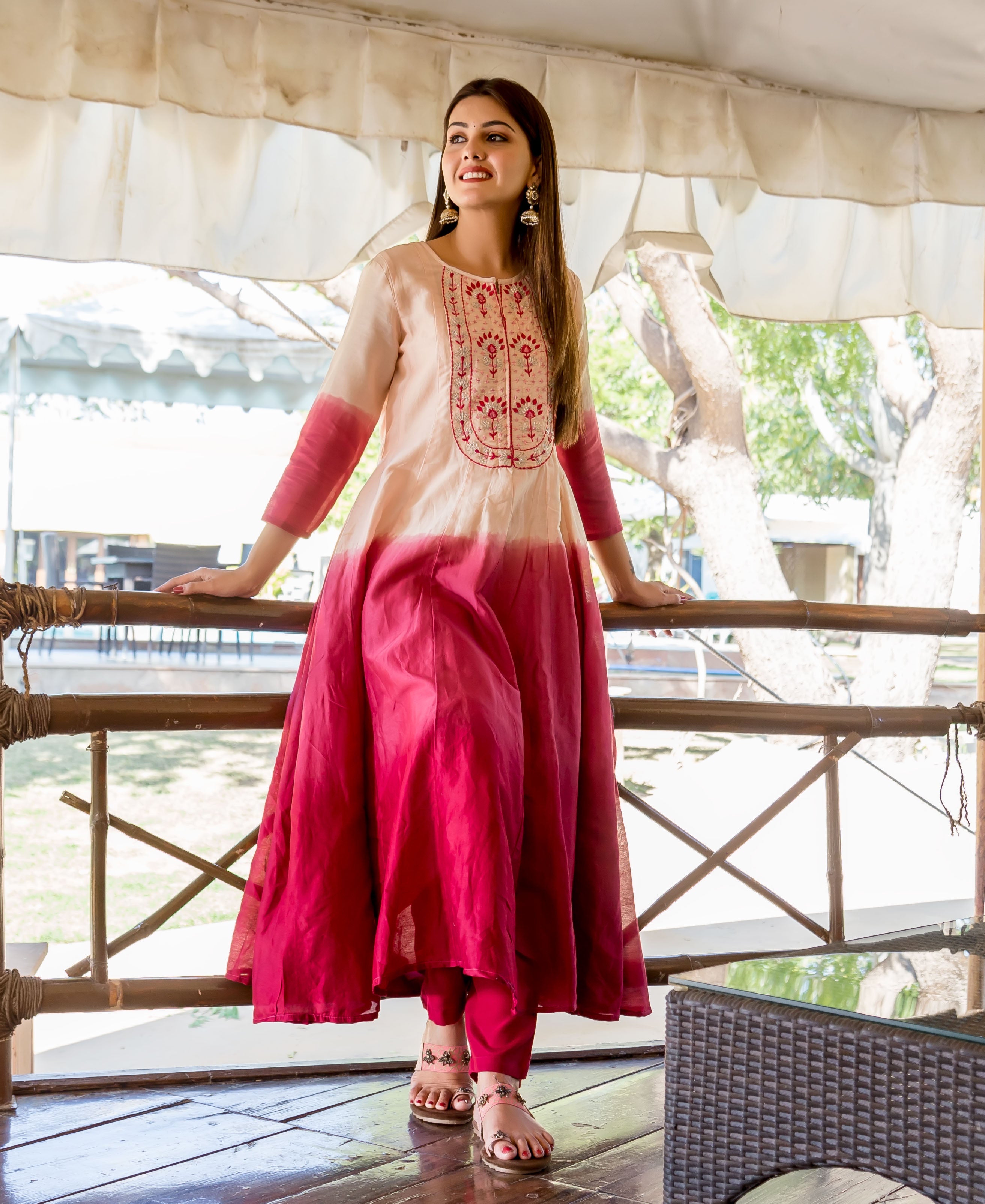 Full-length model in a salmon burgundy ombre embroidered Anarkali kurta with matching pants and sandals.