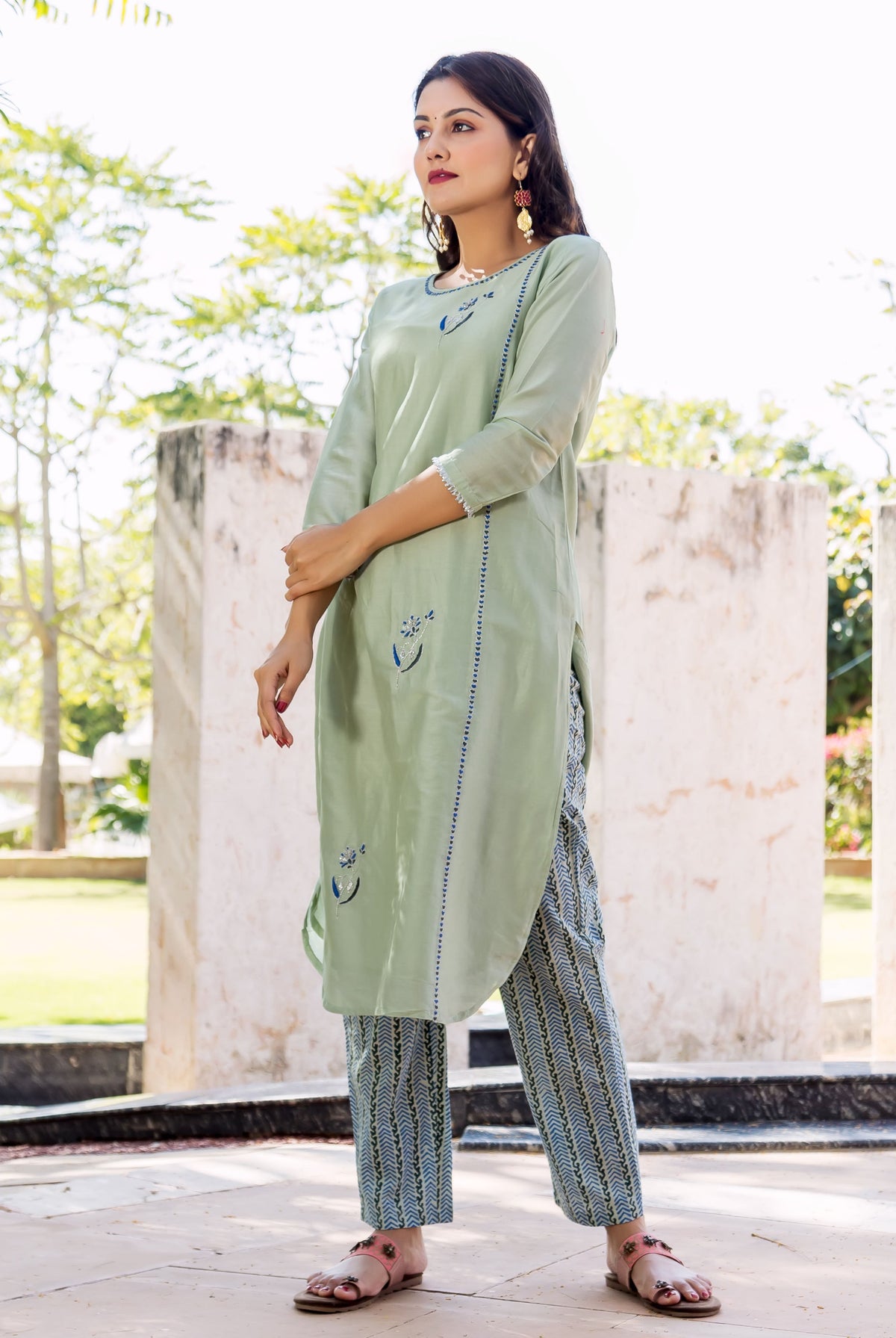 Model wears a pistachio green kurta with blue embroidery and matching blue block-printed pants outdoors.