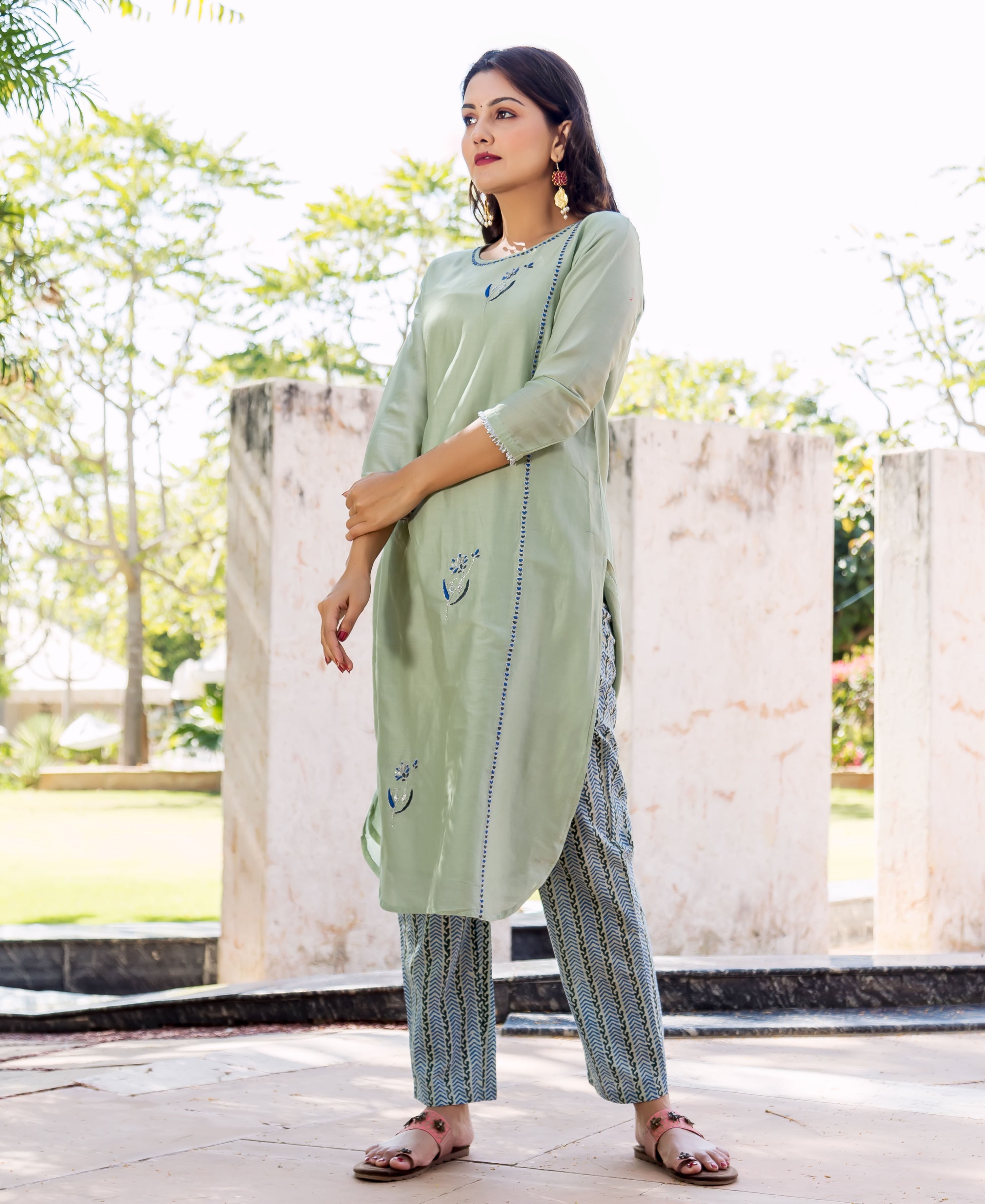 Model wears a pistachio green kurta with blue embroidery and matching blue block-printed pants outdoors.