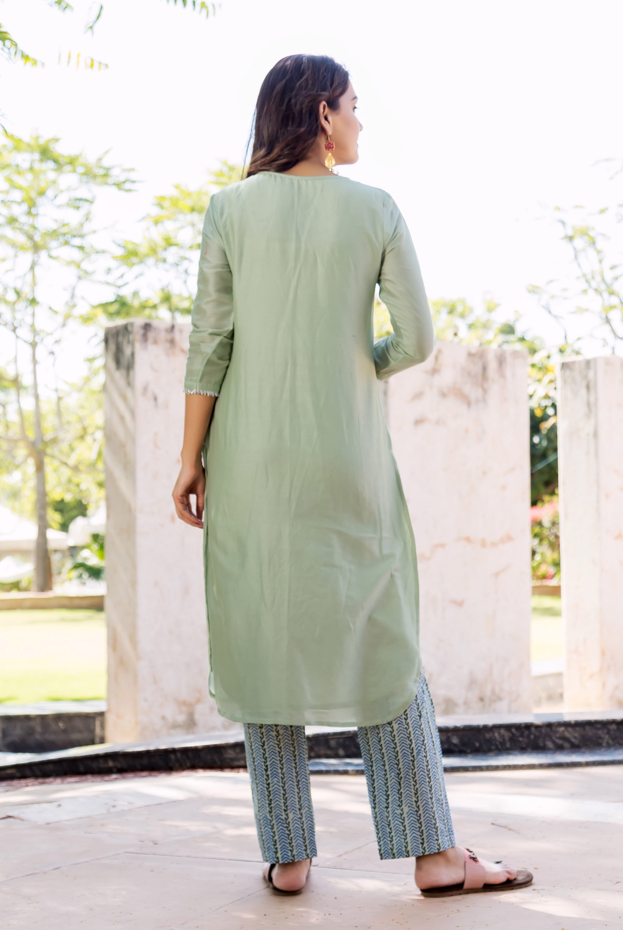 Rear view of model wearing pistachio green kurta and blue hand-block printed pants.